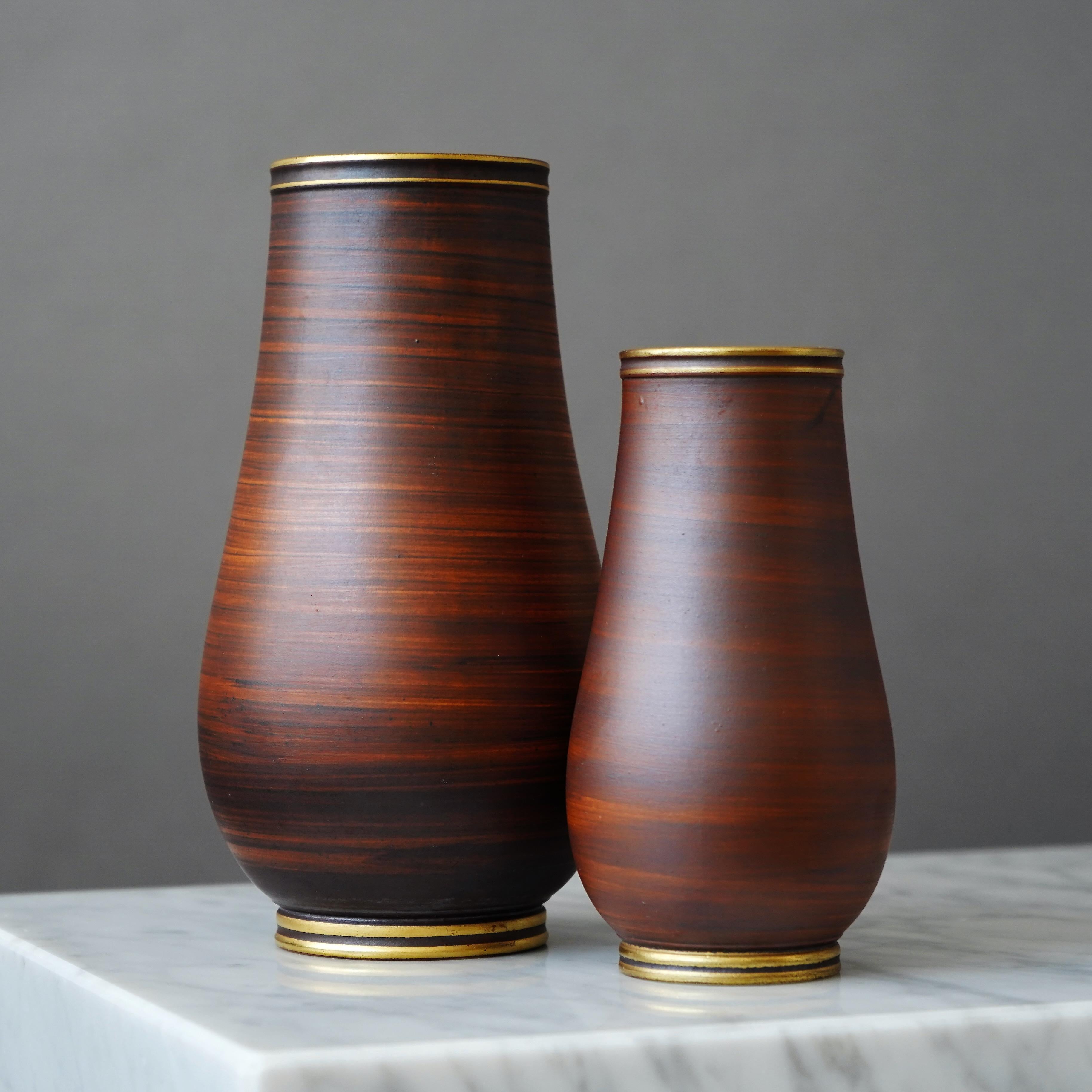 Set of 2 stoneware art deco vases with beautiful brown glaze. Foot and mouth detailed in gold.
Designed by Gunnar Nylund for ALP (Lidköpings Porslinsfabrik), Sweden, 1930s.

Great condition.
Stamped 'ALP', 'Modell Nylund', 'Lidköping, SWEDEN' and