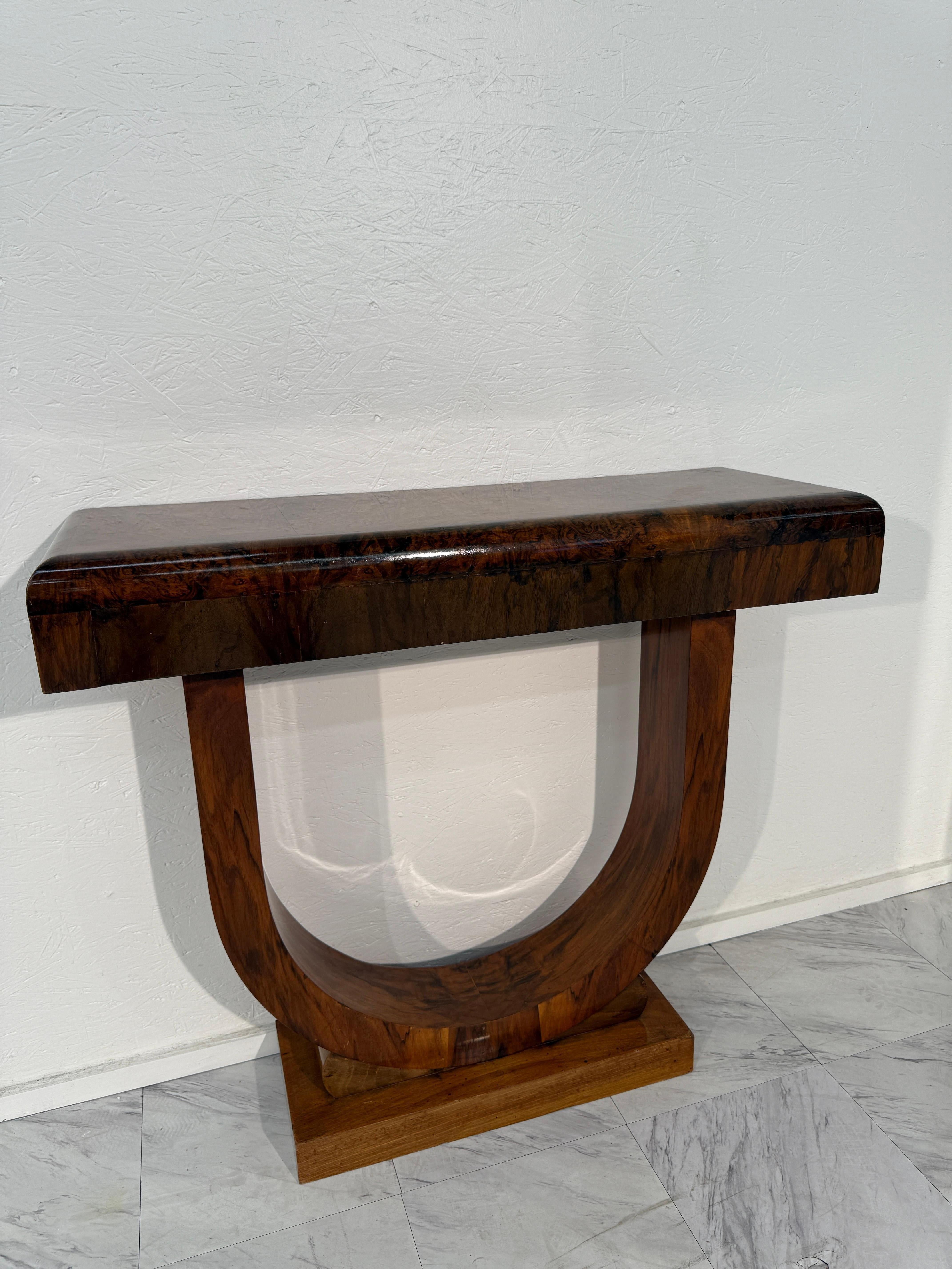 Cette élégante paire de tables console capture la sophistication raffinée du design Art déco. Chaque table est dotée d'un socle en forme de U qui supporte un épais plateau rectangulaire, tous deux fabriqués en placage de ronce de bois joliment