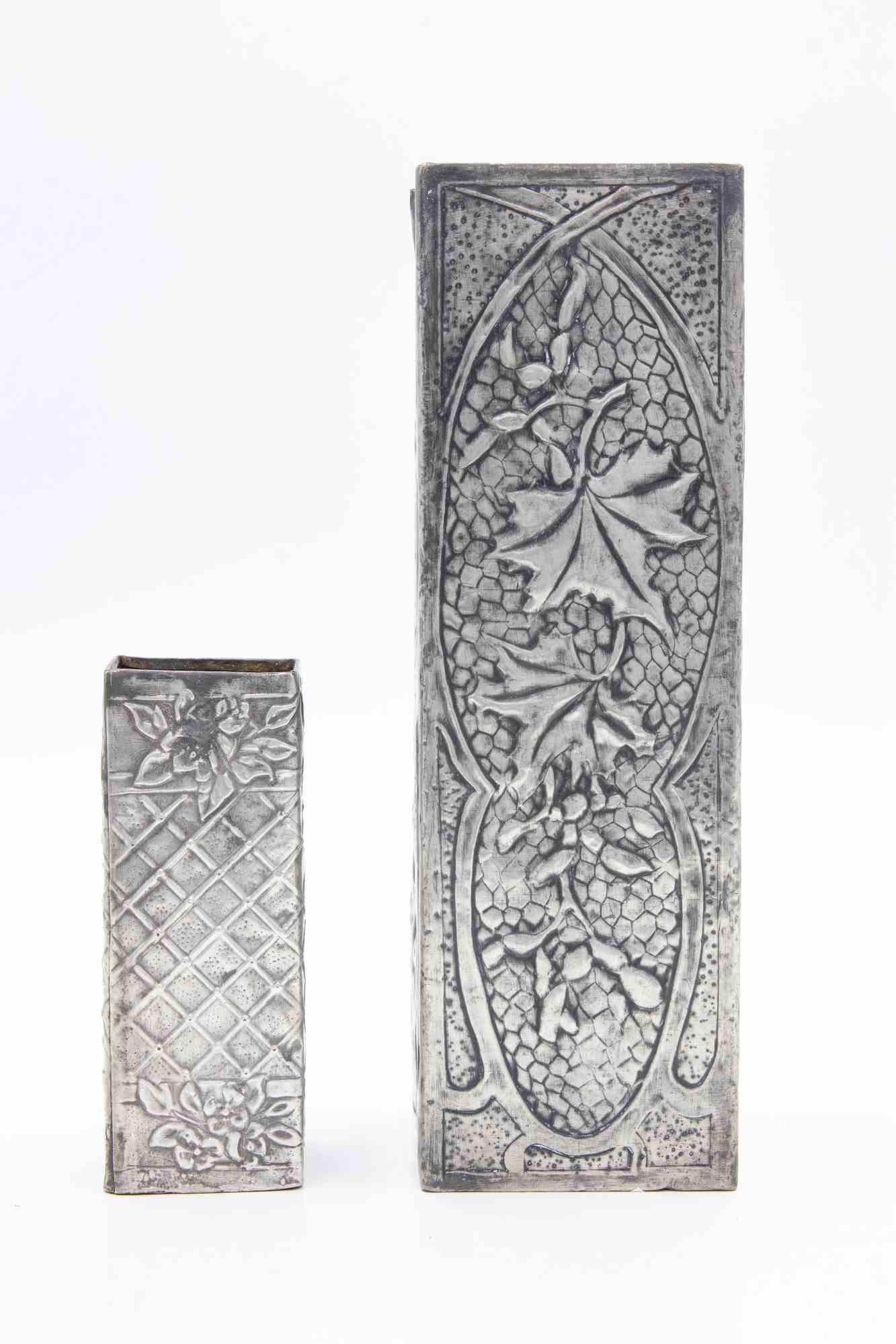 Set di 2 vasi in peltro realizzati all'inizio del XX secolo.

Dimensioni del vaso più piccolo in peltro: H. 10,7 x L. 4,5 x L. 4,5 cm.

Dimensioni del vaso Petwer: H. 22,7 x L. 7 x 7 cm. 

Ottime condizioni.