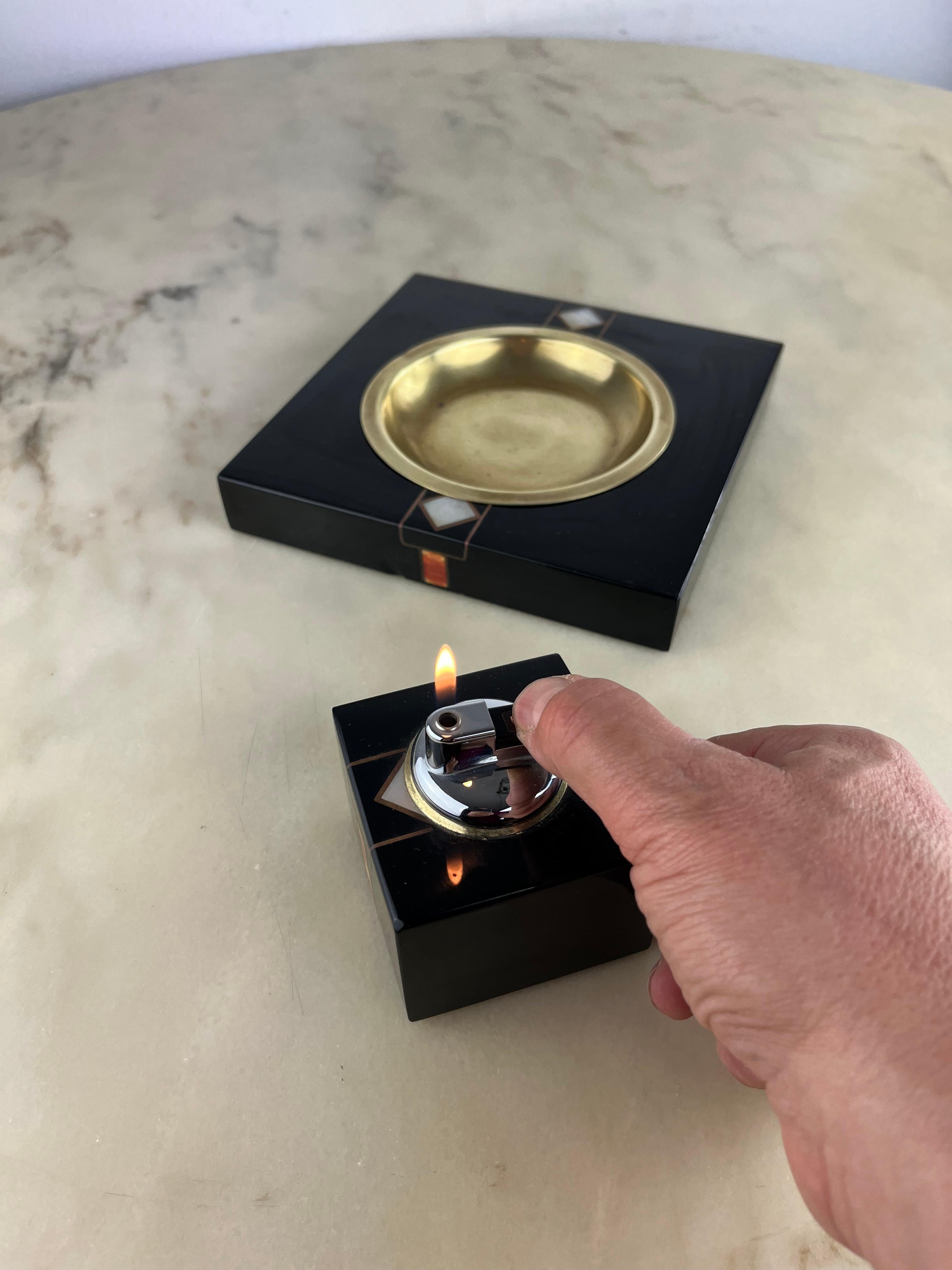 Set of 2 Ashtrays and table lighter Vintage, Italian design, 1970s.
The ashtray is made of brass and decorated wood. It measures 20 cm x 20 cm x 3 cm high.
 The lighter measures 7.5 cm x 7.5 cm and is 9 cm high.
Intact and in good condition, small