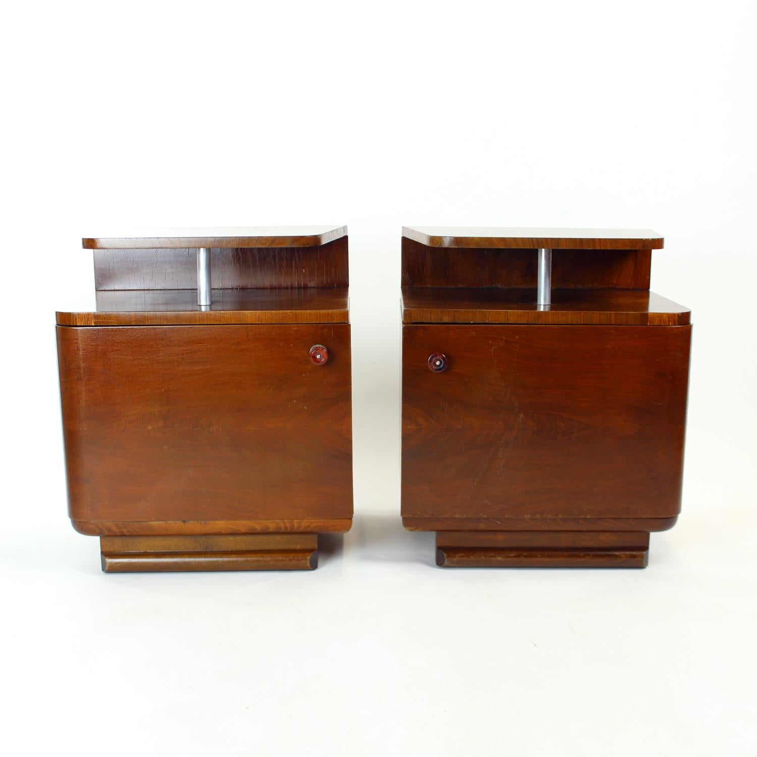 Beautiful, fully restored set of two bedside tables. They were produced in Czechoslovakia in 1950s. The tables are made of wood with dark oak veneer. Very interesting design with each table having one compartment with plain doors on piano hindges.