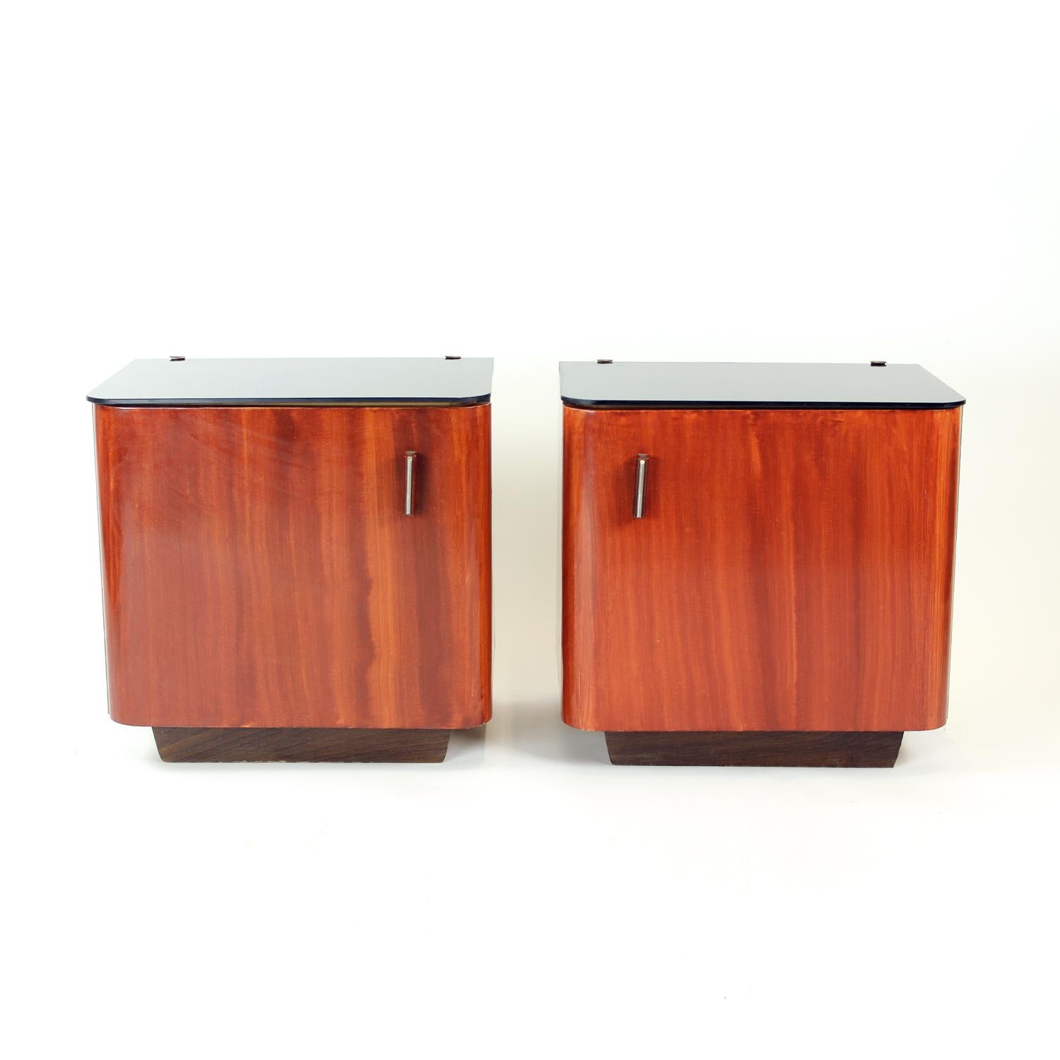 Beautiful vintage bedside tables produced in Czechoslovakia in 1960s. The tables were refinished in 1970 into the current condition. The top board is made of black metallurgical glass in excellent condition. The tables show only minor age patina,