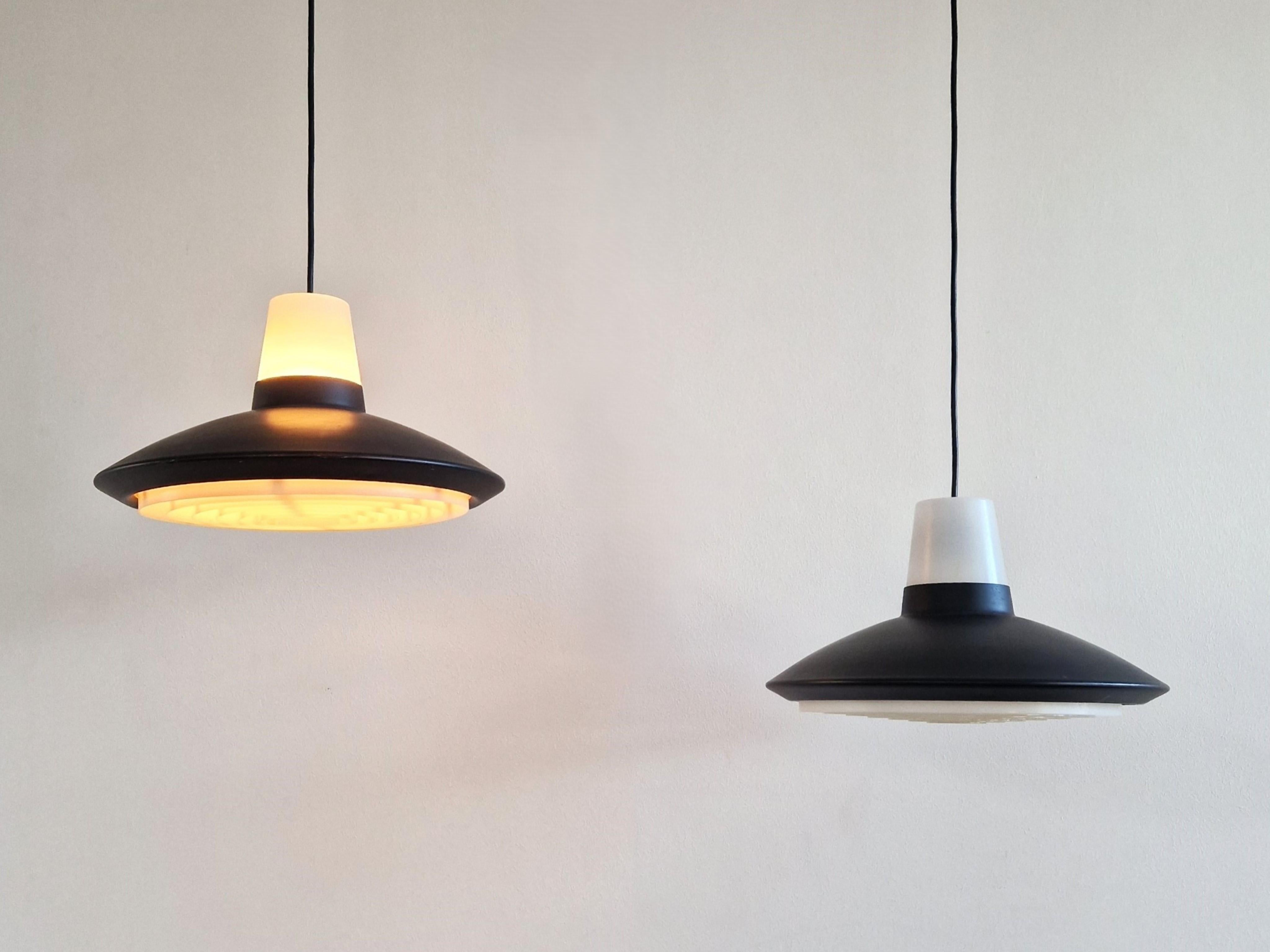 Questa grande lampada a sospensione è stata progettata per Nordisk Solar in Danimarca negli anni '60. Il paralume in metallo nero è abbinato a parti in plastica bianca nella parte superiore e al diffusore in quella inferiore, che diffondono la luce