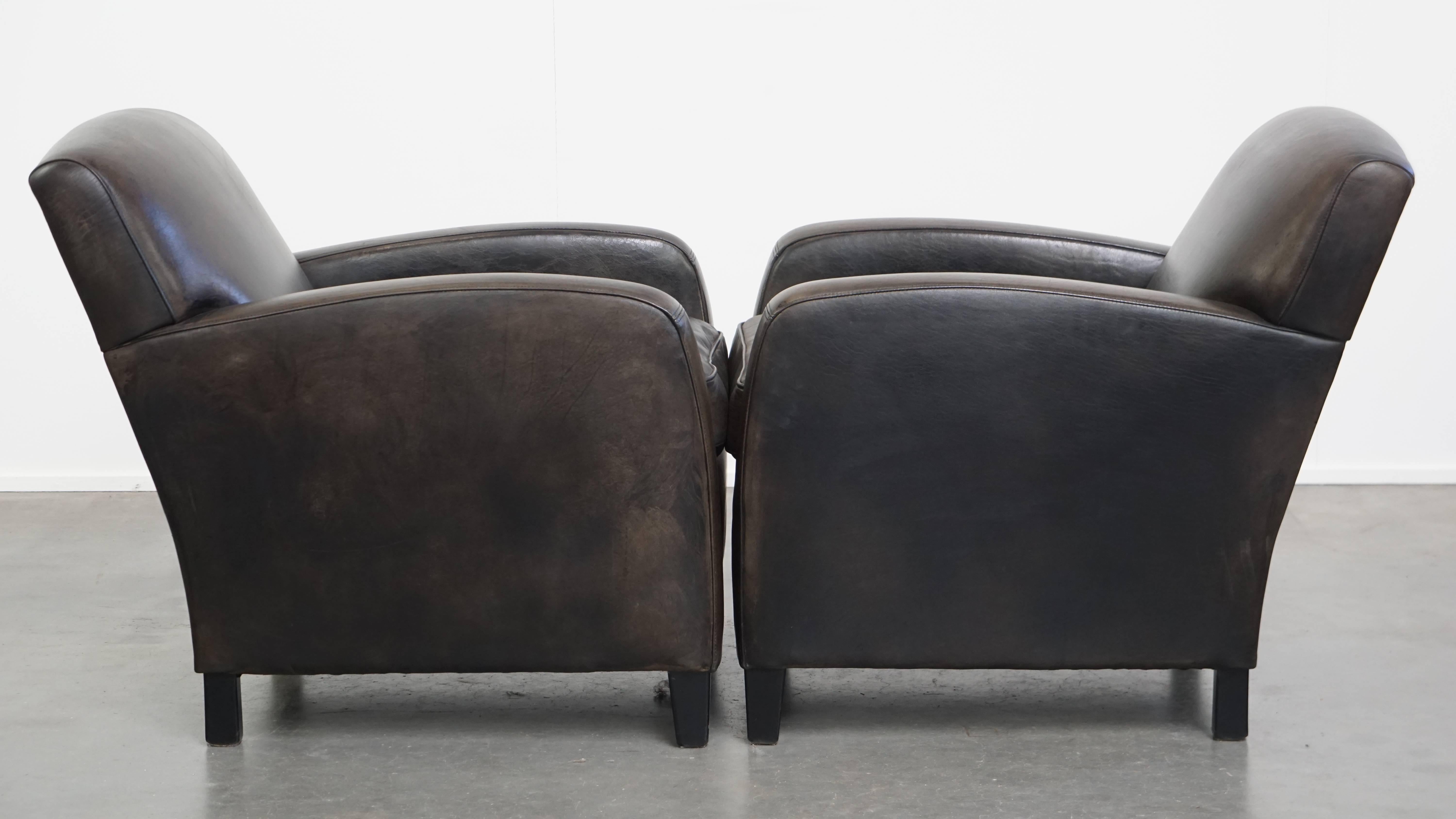 Dieses Set aus zwei schwarz/grauen Sesseln aus Schaffell lässt sich aufgrund seines Designs und seiner zeitlosen Erscheinung problemlos in fast jedes Interieur einfügen. Sie sind mit einem losen Sitzkissen ausgestattet und bieten Ihnen einen