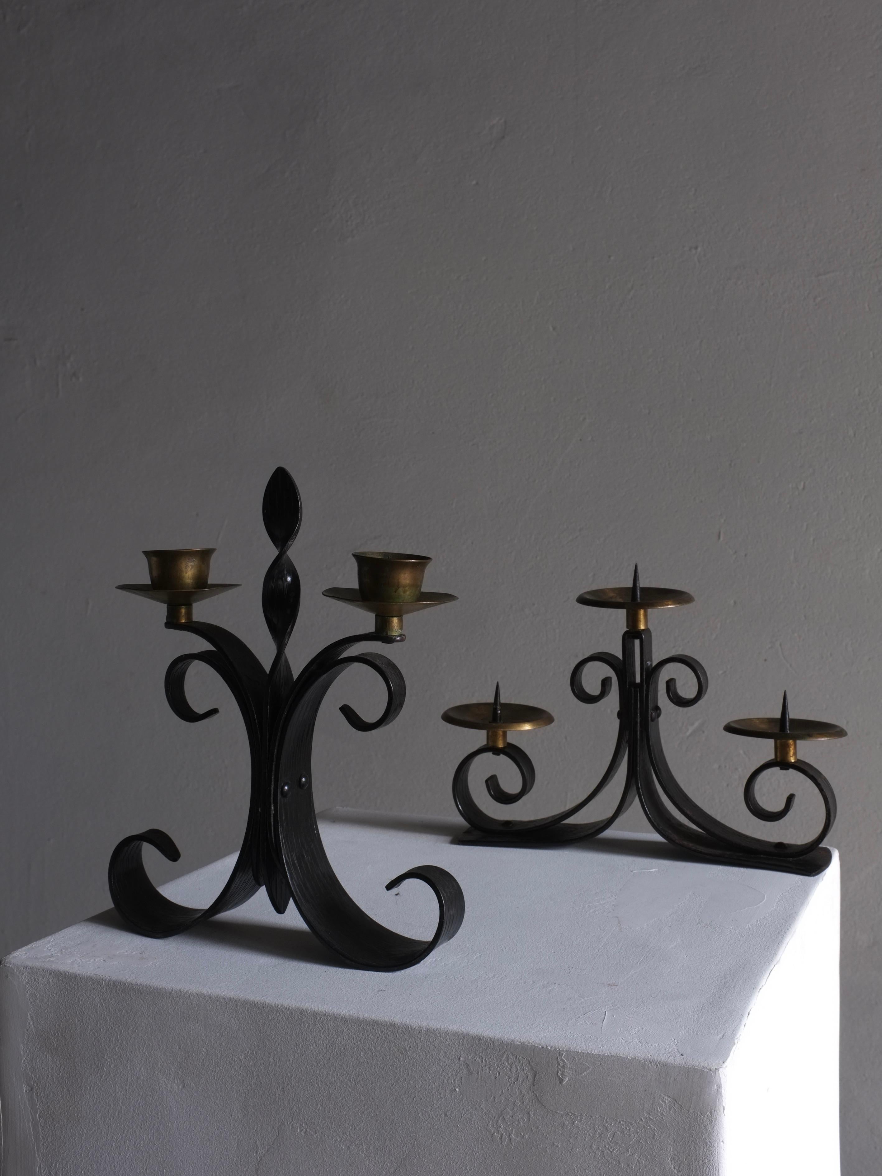 Set of two vintage brutalist metal candle holders with three and two arms. Black iron base, brass cups.

Additional information:
Country of manufacture: Latvia
Period: 1970s 
Dimensions: W 17.5 cm W 21.5 cm x D 5.5 cm, Cup Diameter 6.5 cm D 4 cm,