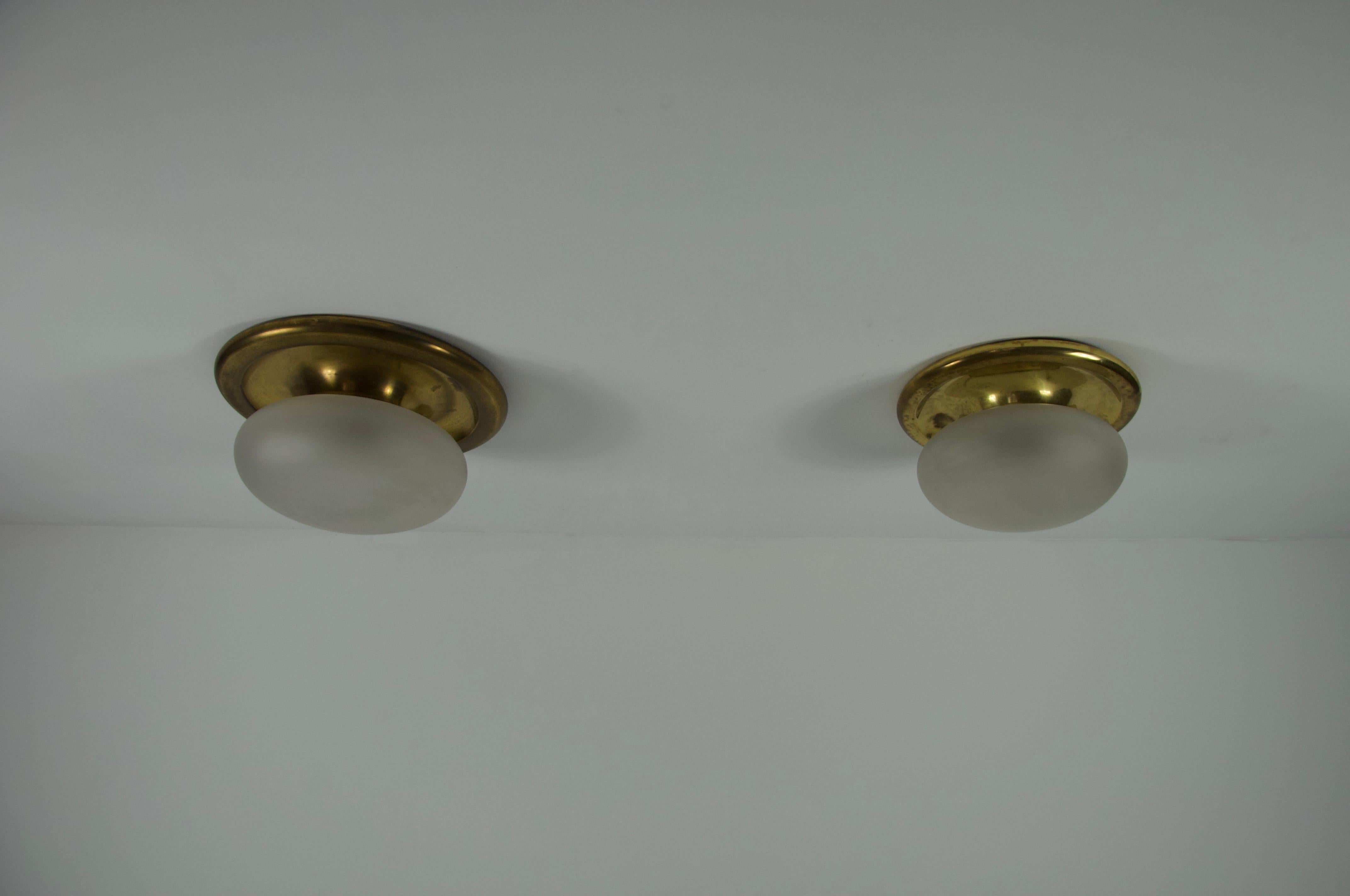 Cette paire de lampes encastrées du milieu du siècle dernier, provenant d'Italie et datant des années 1960, est un exemple de design intemporel et d'élégance discrète. Les luminaires sont dotés d'une base ronde classique en laiton qui s'adapte
