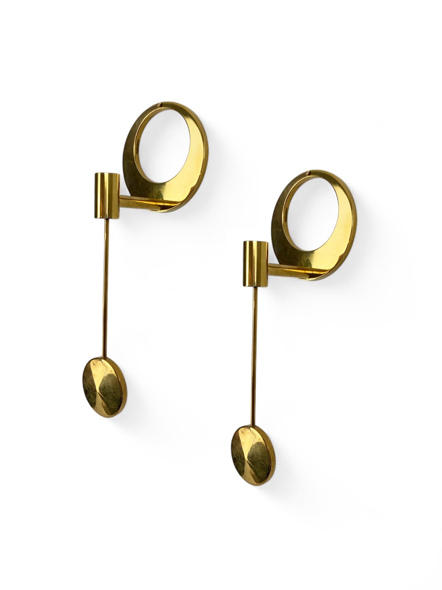 A set of 2 Modernist candle-holders in solid brass, made in the 1960-70s.

Circular wall base, the socket fixed in a pendulum. To be used with so-called 