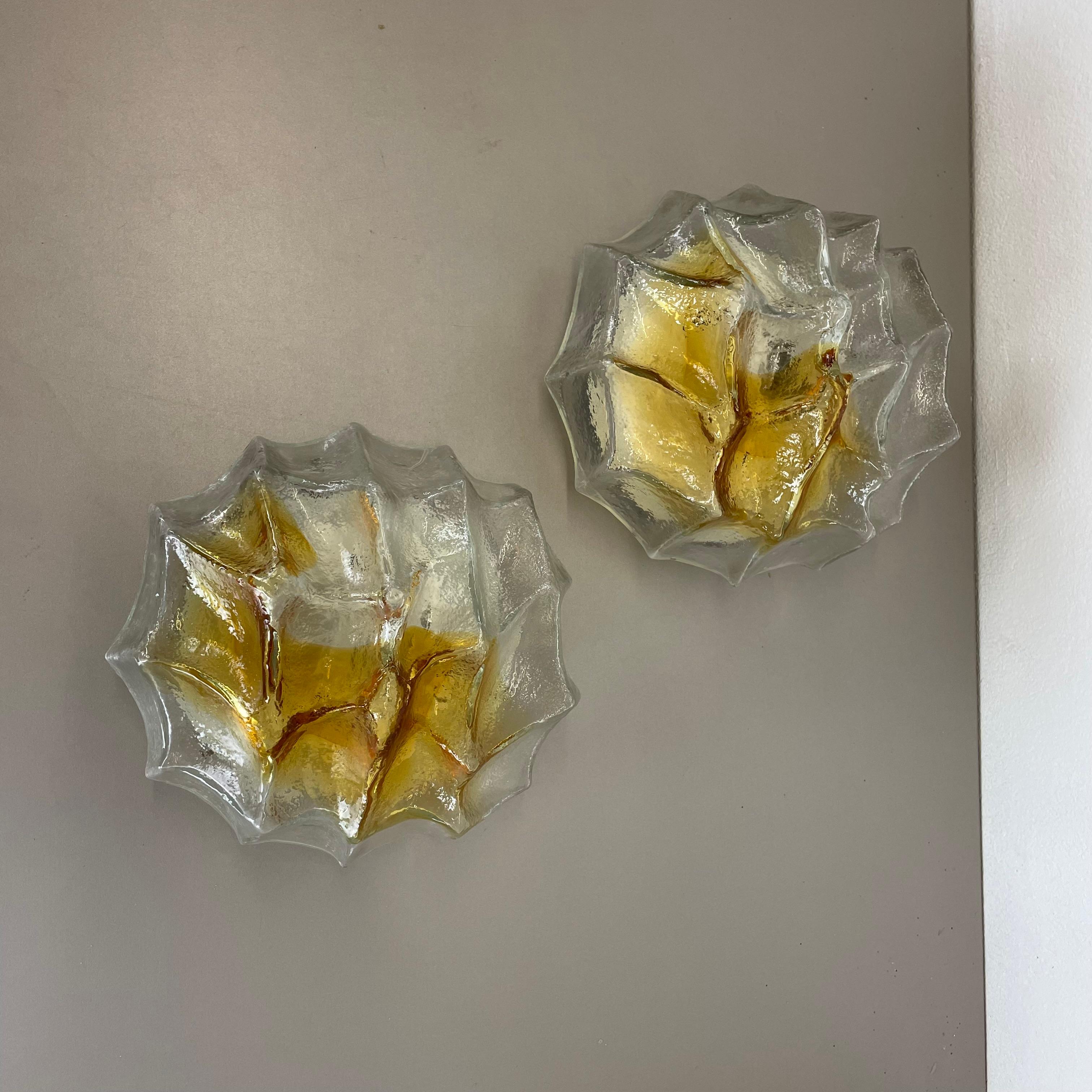 Article:

set of two wall lights


Producer:

Glashütte Limburg, Germany



Origin:

Germany



Age:

1970s



Original 1970s set of modernist German wall Light made of high quality Murano glass with a a rock brutalist surface optic in a combination