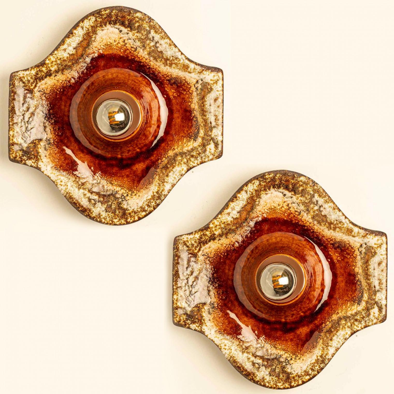 Magnifique ensemble de deux appliques ovales en céramique, fabriquées en Allemagne vers les années 1970.

La glaçure présente des gradients de couleurs chaudes.

Nous avons utilisé des ampoules transparentes (voir images), mais les ampoules