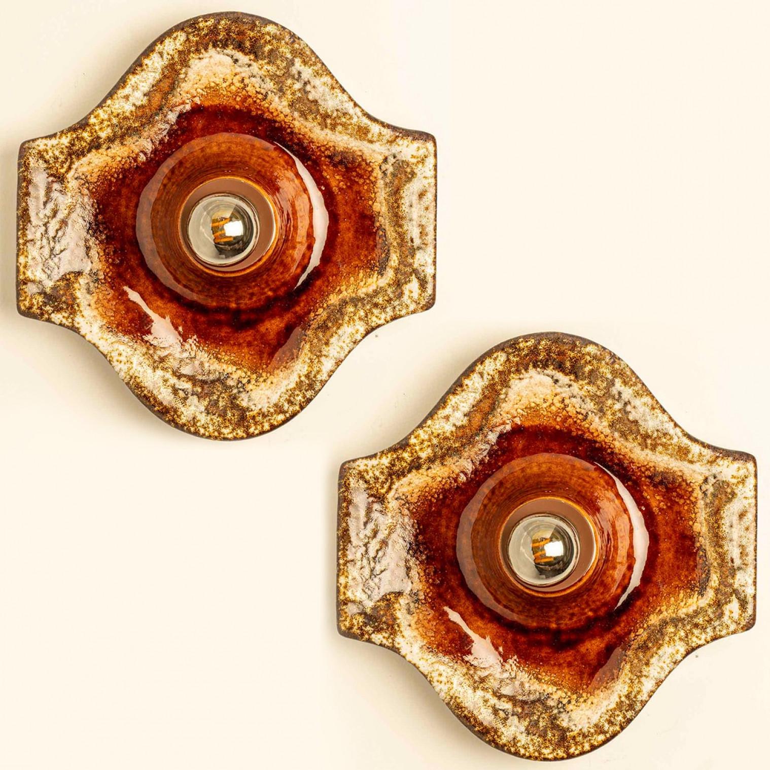 Magnifique ensemble de deux appliques ovales en céramique, fabriquées en Allemagne vers les années 1970.

La glaçure présente des gradients de couleurs chaudes.

Nous avons utilisé des ampoules transparentes (voir images), mais les ampoules