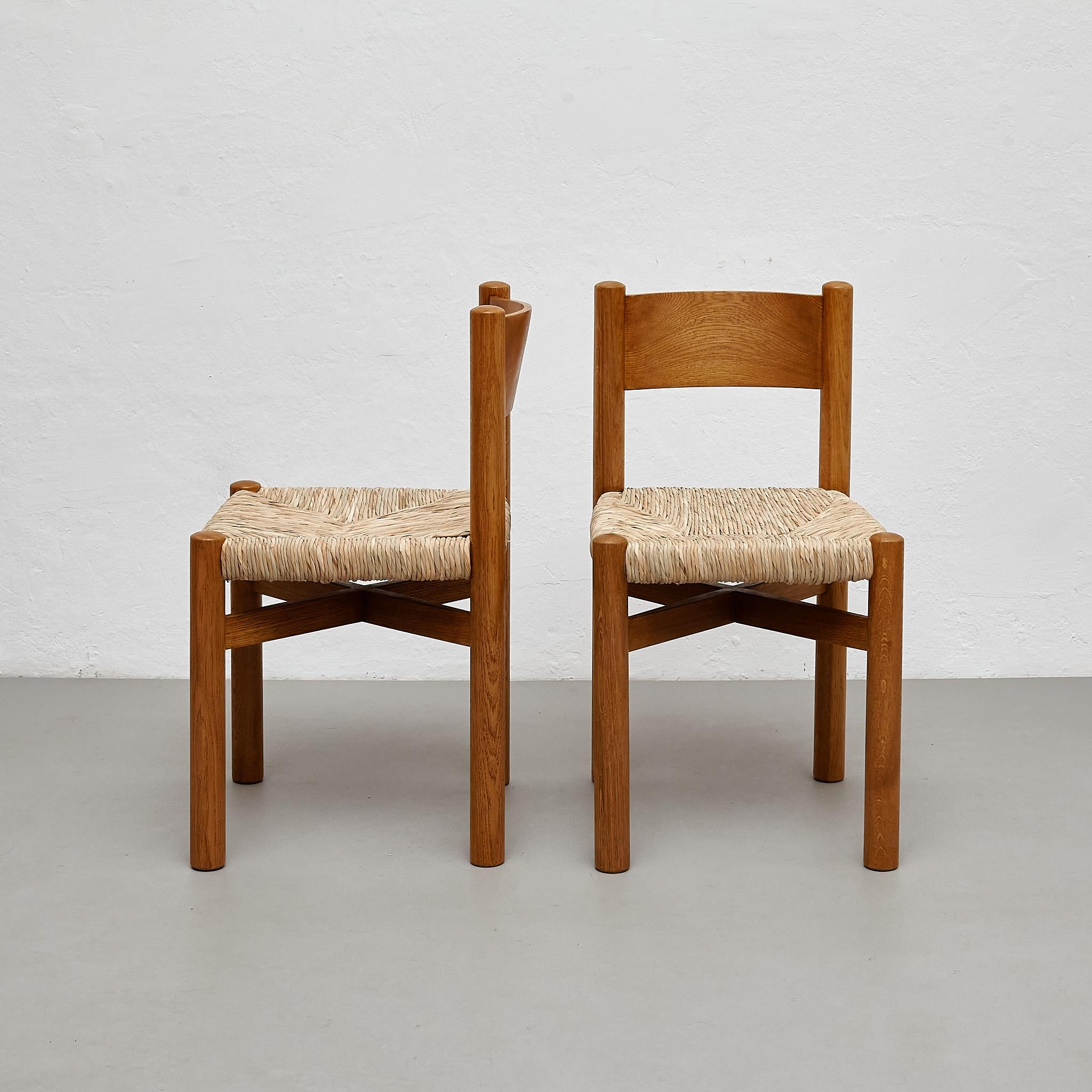 Set of 2 chairs After Charlotte Perriand.

By unknown manufacturer, from France, circa 1980.

Dimensions:
D 39 cm x W 46 cm x H 74 cm (SH 44 cm)

Materials:
Wood and rattan.

In original condition, with minor wear consistent with age and use,
