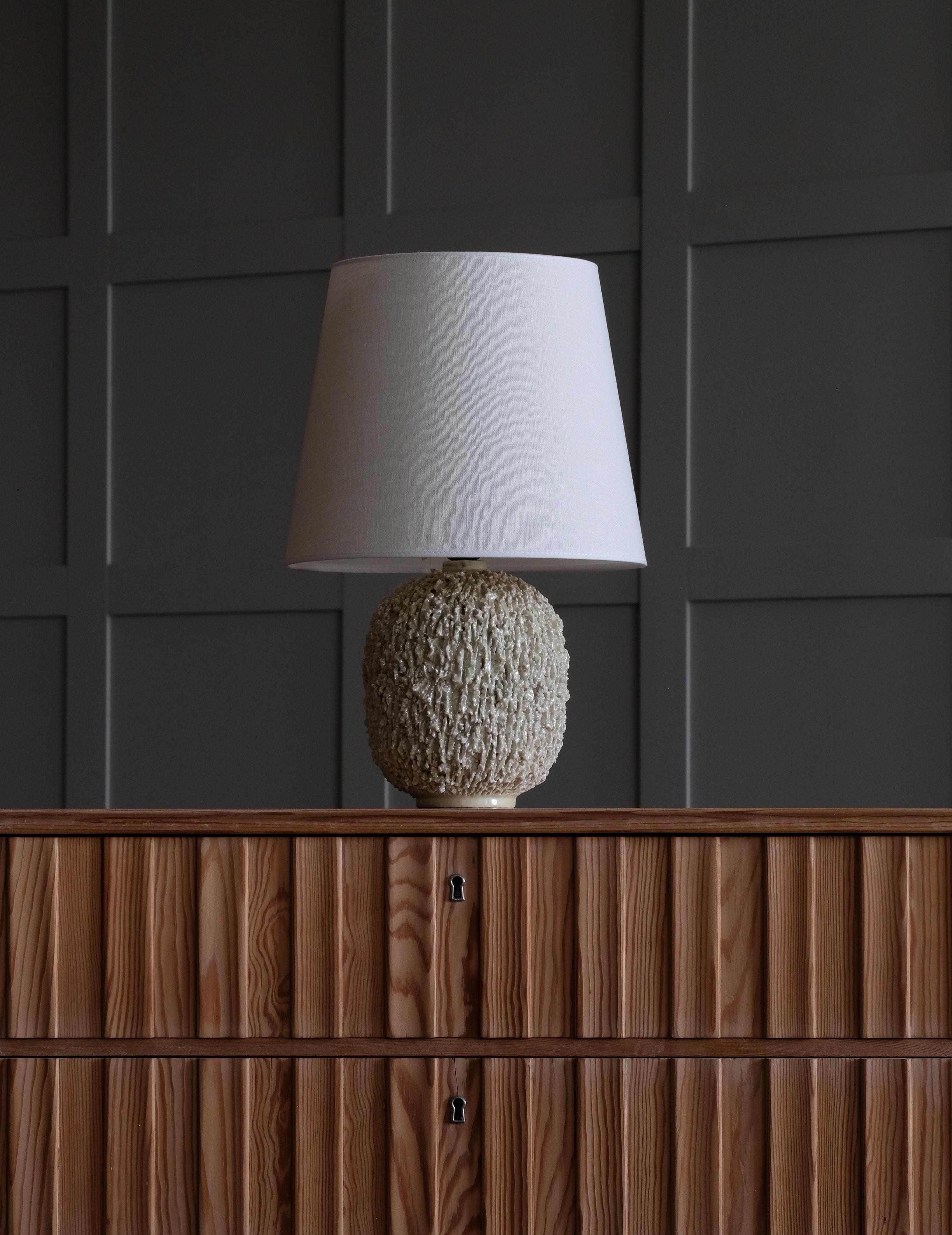 Lampe en céramique de forme bulbeuse par Gunnar Nylund, composée d'argile chamottée et émaillée d'une glaçure lustrée de couleur blanche. Produit par Rörstrand. Estampillé. Lot de 2 disponibles.
Remarque : le prix indiqué est celui d'une (1) lampe