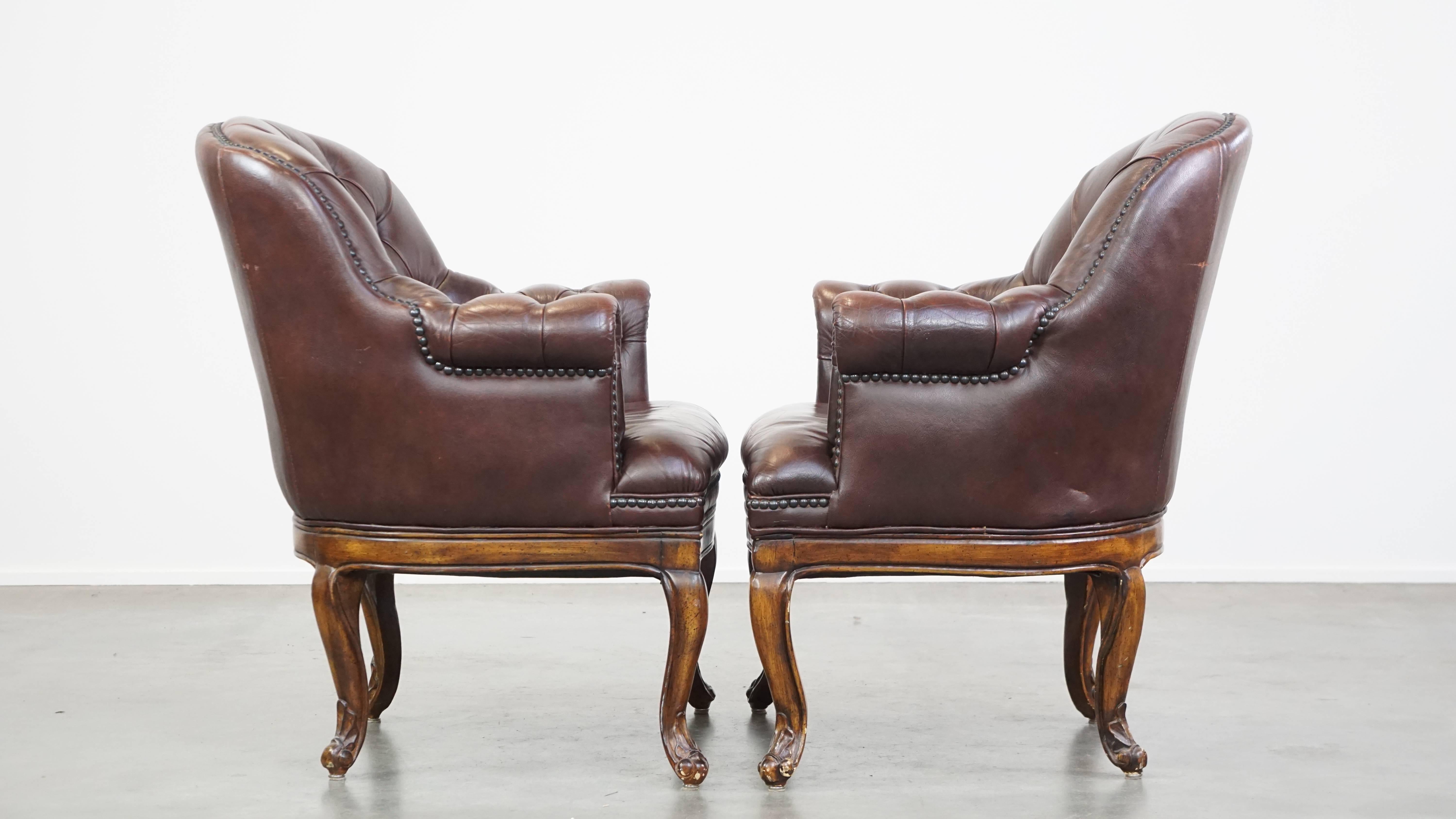 Cet ensemble de 2 fauteuils en cuir foncé exsude le charme et l'élégance classiques anglaises intemporelles. Avec leurs formes et leurs pieds gracieux, ces fauteuils constituent un complément fantastique pour les amateurs de meubles Chesterfield.