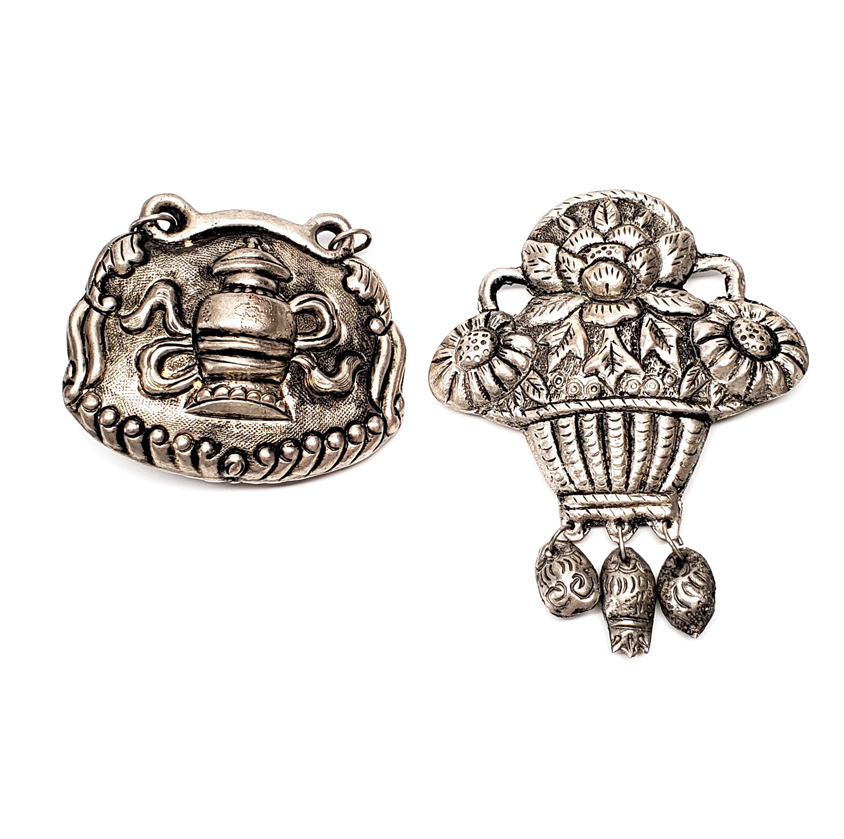 Set of 2 antique Chinese silver amulet pendants.

Amulets feature a basket of flowers, and a urn, the same design is on both sides of each amulet. Large, substantial amulets with highly detailed design and beautiful craftsmanship.

Flower basket