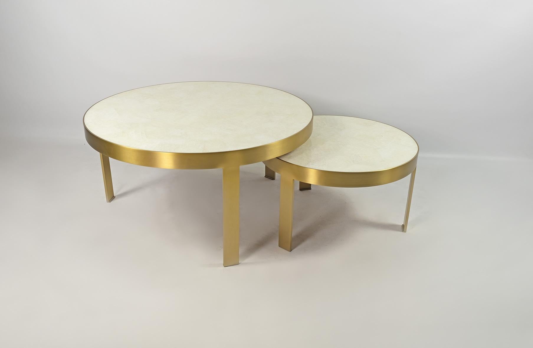 This set of 2 coffee tables is made of a white rock crystal marquetry top.
The structure and the legs are made of a thick brushed brass.
Each table is circular and it has three legs.
 
The dimensions of the tables are:
Large: Diam 31.5