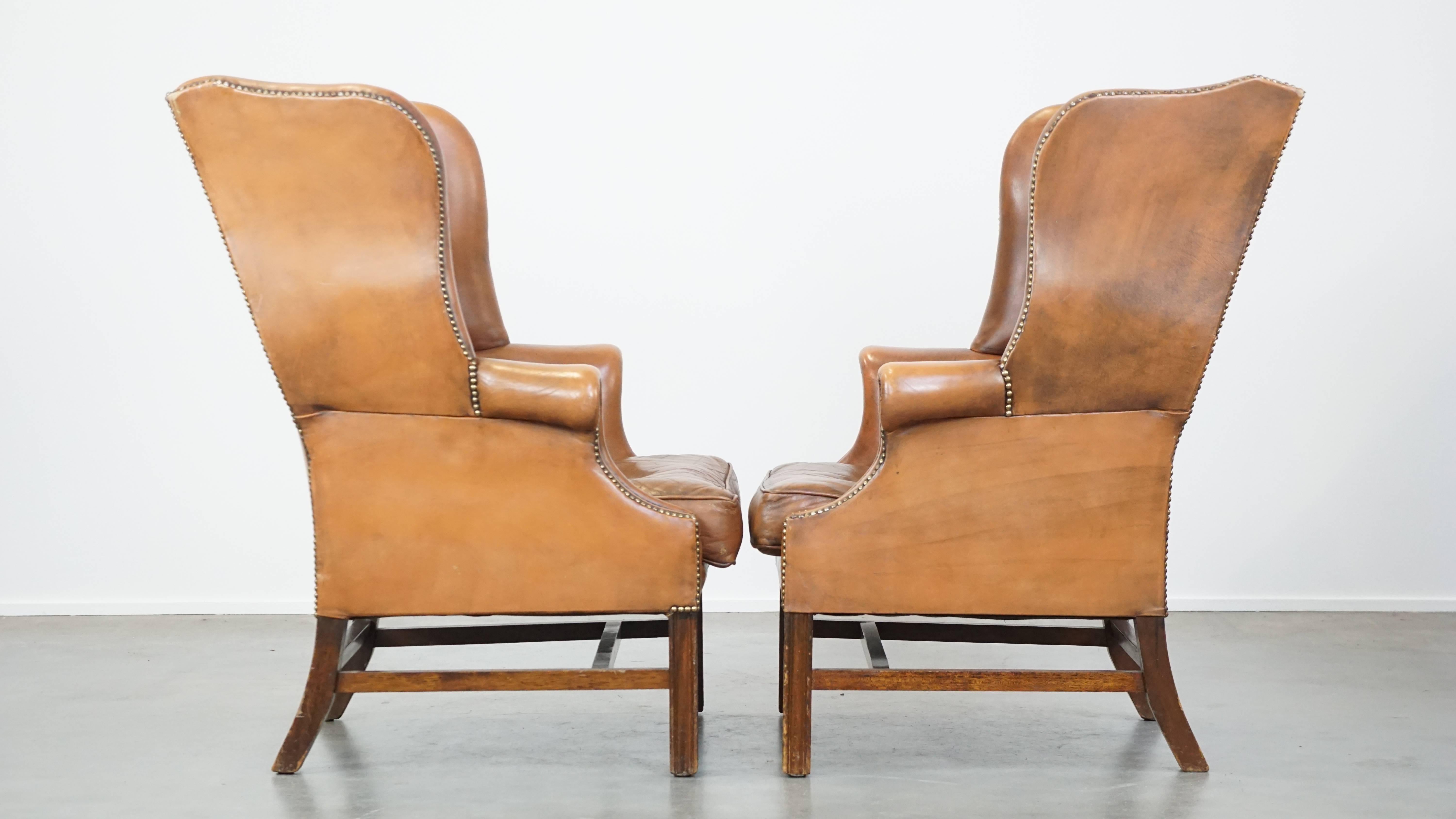 Luxury, character, and style—these three words perfectly describe this set of two genuine leather English Chesterfield wingback armchairs. They feature a light cognac color and a distinctive, timeless appearance. With their loose seat cushions and