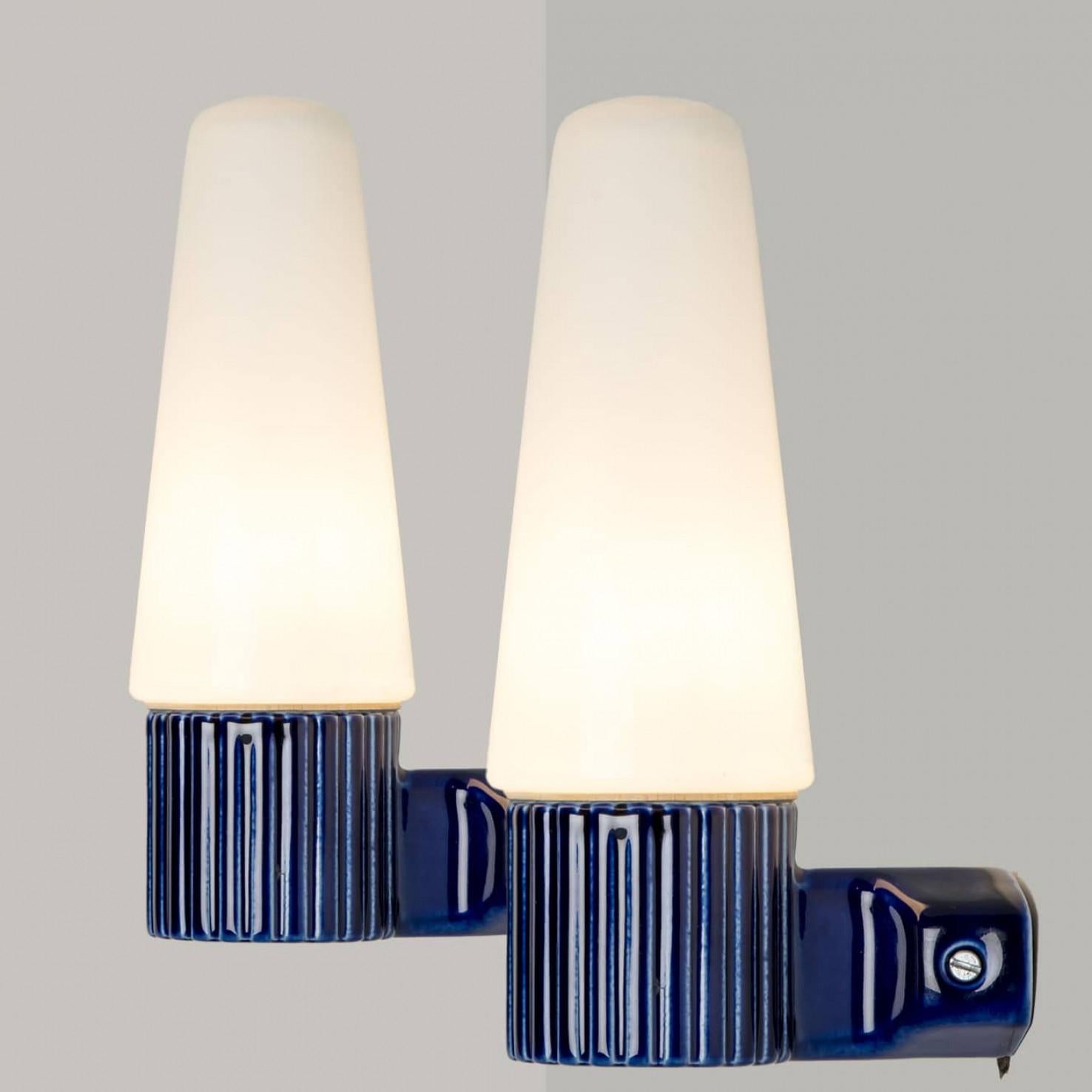 Paire de superbes appliques murales, fabriquées par Sigvard Bernadotte dans les années 60. Les lampes sont constituées d'un cône blanc en verre, maintenu par une poignée en céramique cobalt, créant ainsi un effet de classe et d'élégance.



Le