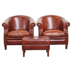 Ensemble de 2 fauteuils club en cuir de vachette de couleur cognac avec ottoman assorti