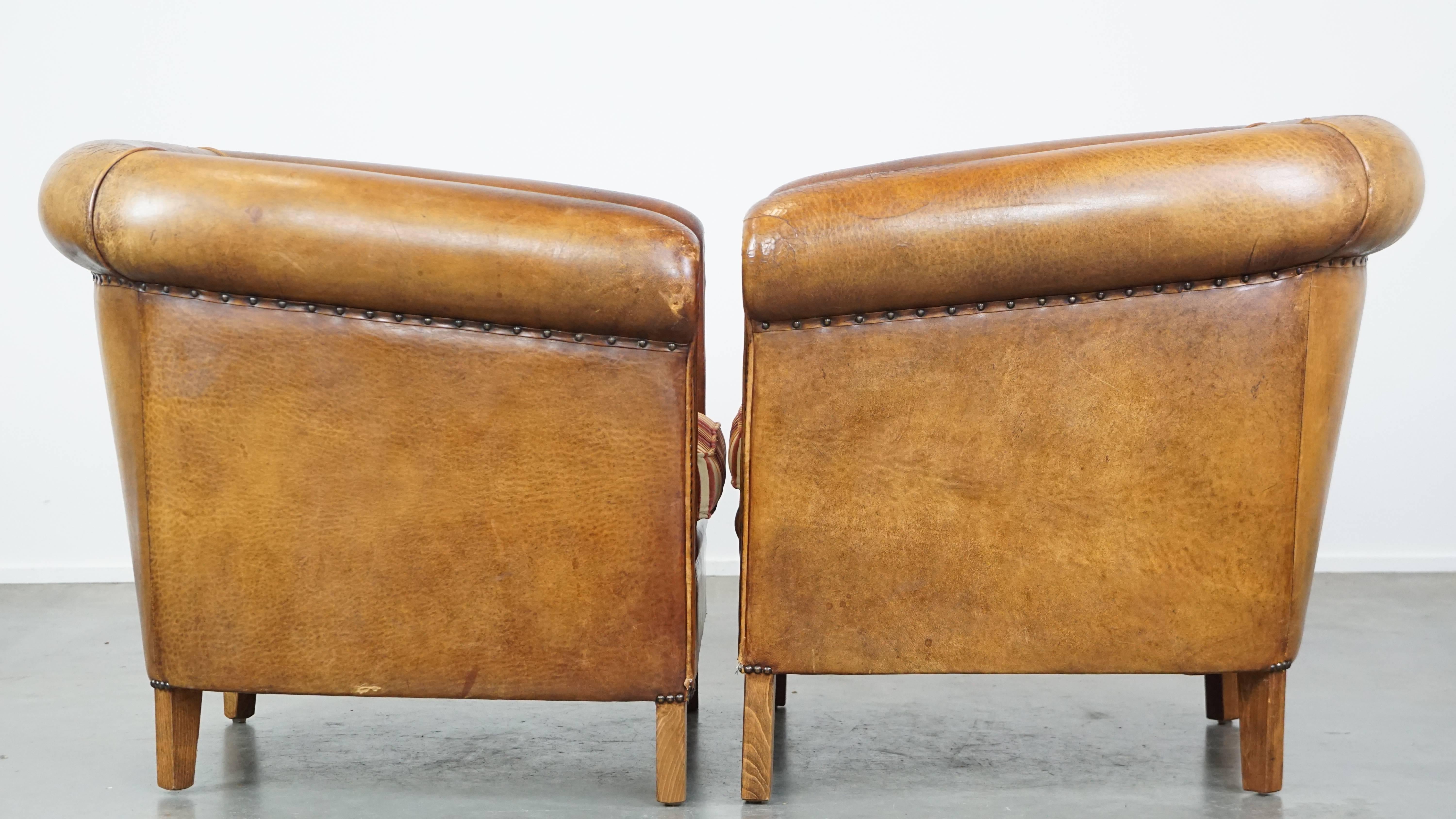 Angeboten wird dieses Set aus 2 cognacfarbenen, charaktervollen Vintage-Schafsfell-Clubsesseln mit bunten Stoffsitzkissen.

Dieses Set aus 2 tollen Vintage-Schafsfell-Clubsesseln ist ein echter Blickfang, der in keiner Einrichtung fehlen sollte. Sie