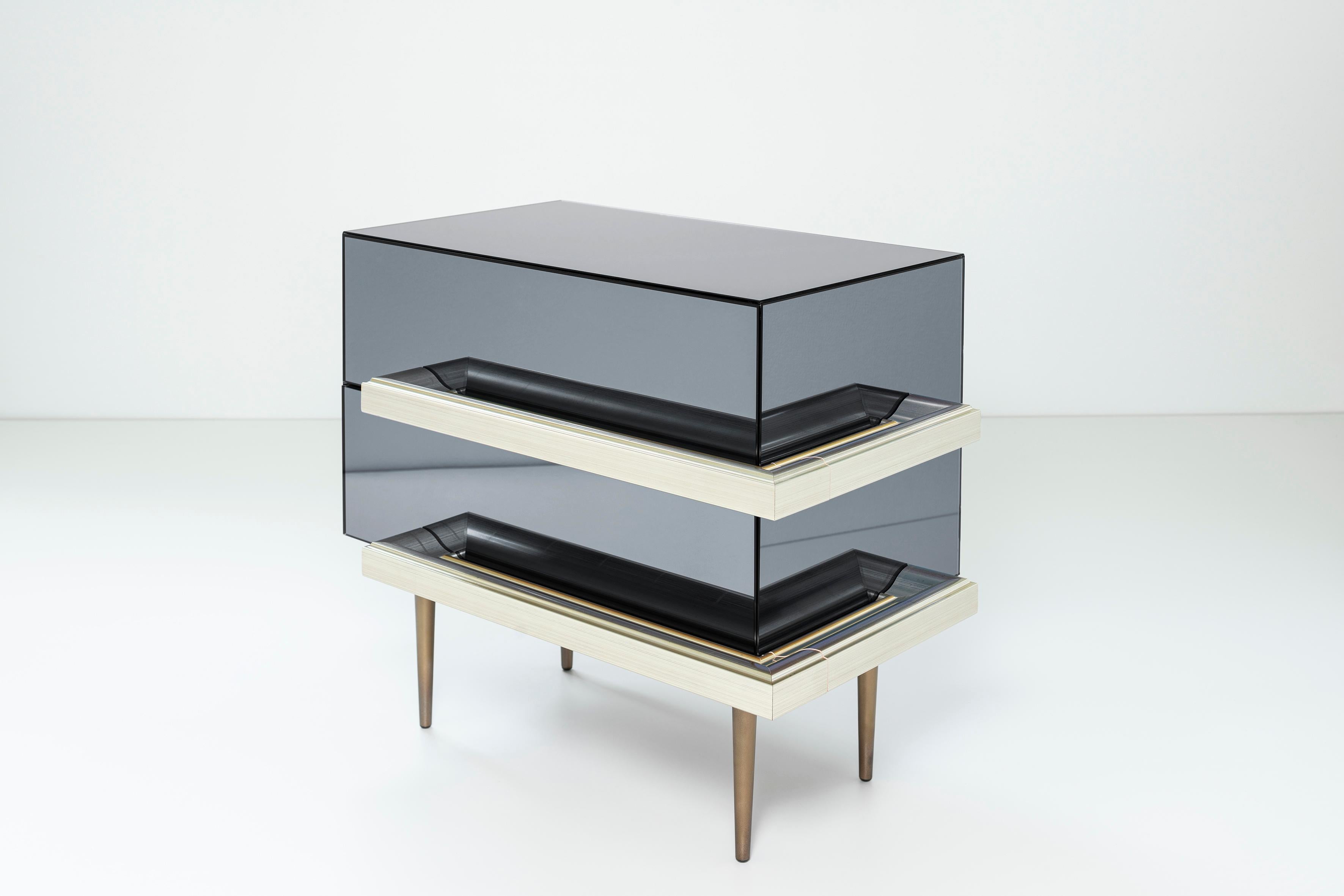 2 drawers mirrored nightstands with finest champagne picture frame molding handles. Dark walnut finish interior and fade brass metal finish in the legs. Mirror color: Silver.

The traditional French mirror cabinet is reinterpreted leaving the
