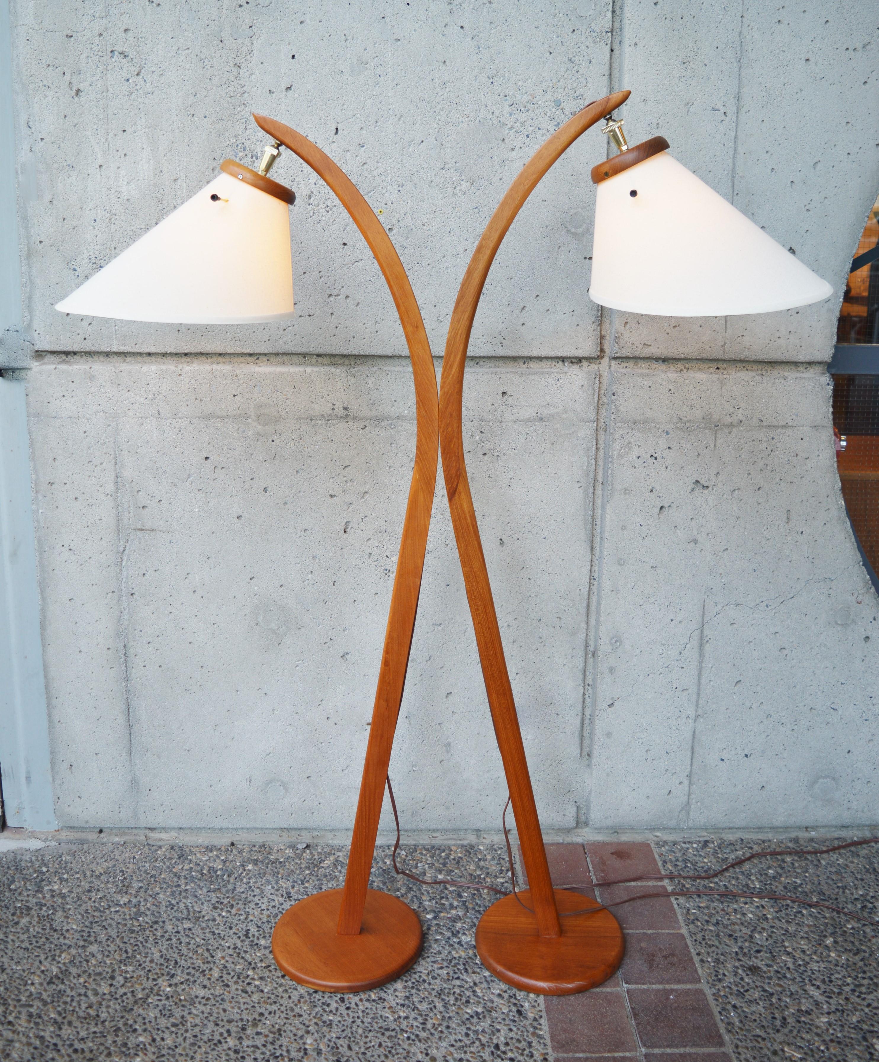 This iconic pair of Danish modern teak arc lamps are perfect as their small footprint allows them to fit in any room. The gentle arc and Classic bonnet shades complete the look. The brass neck hardware is strong and holds up the lampshades as
