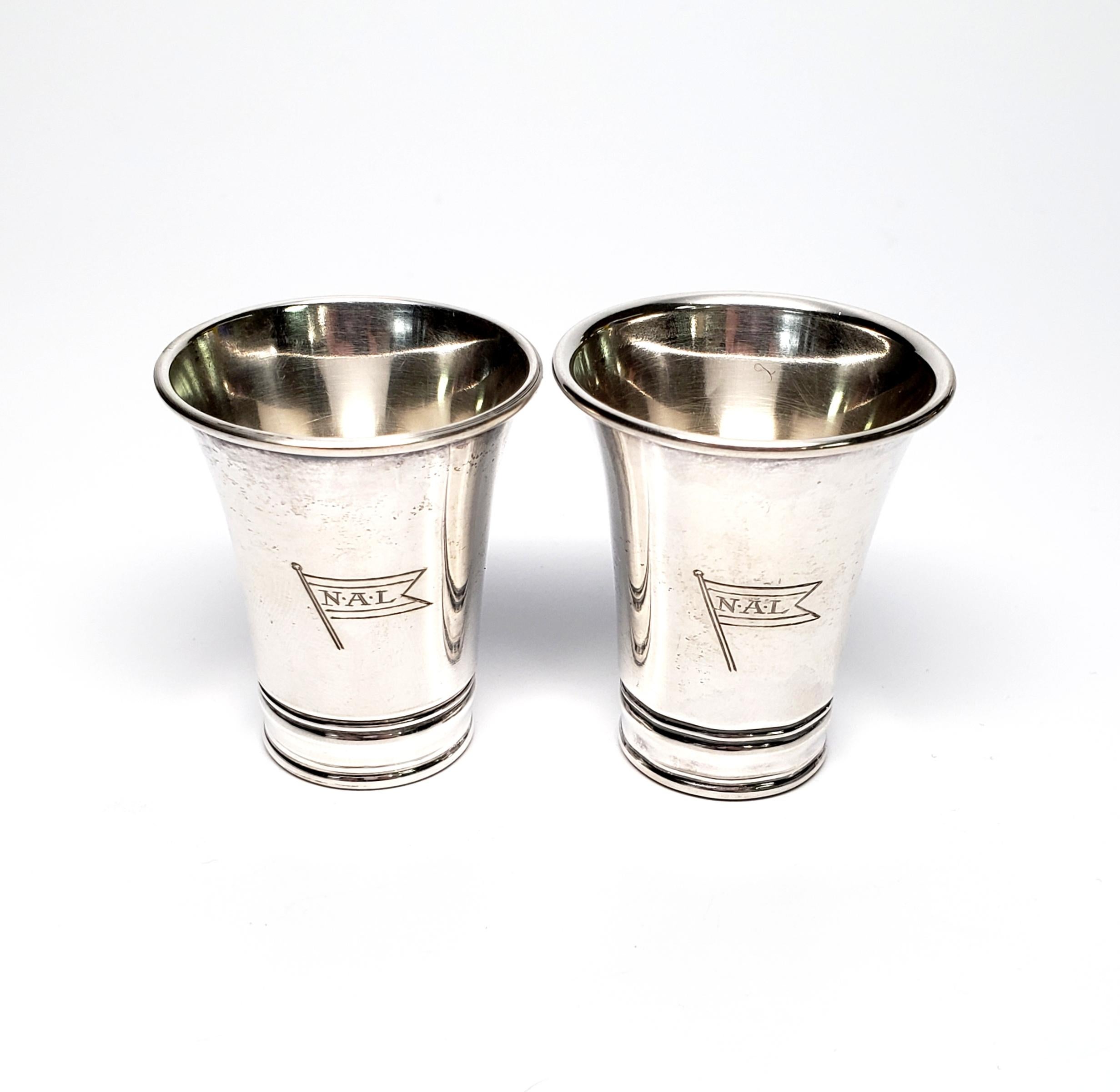 Set of 2 830 silver Norwegian American Line souvenir cups by David Andersen.

These 2 small cups are slightly different sizes and feature the NAL flag etched on each cup.

The smaller cup measures approx 1 5/8