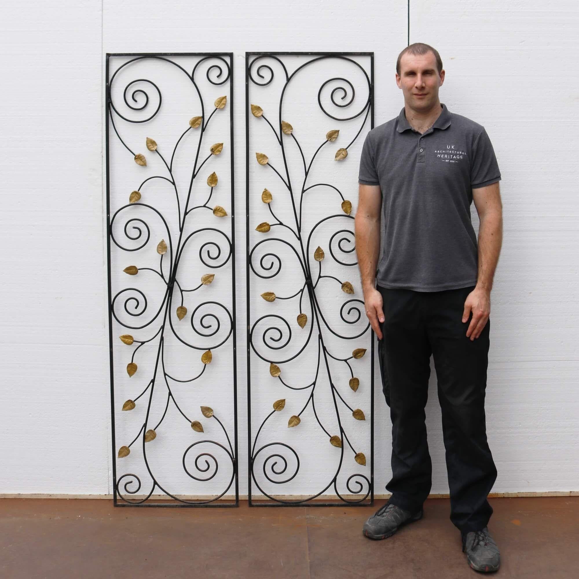 This stunning pair of decorative wrought iron panels date from the 1950s. Made at the hand of a talented blacksmith, each feature gold painted leaves among ornate scrollwork that makes an incredibly beautiful set of panels for a garden or interior.