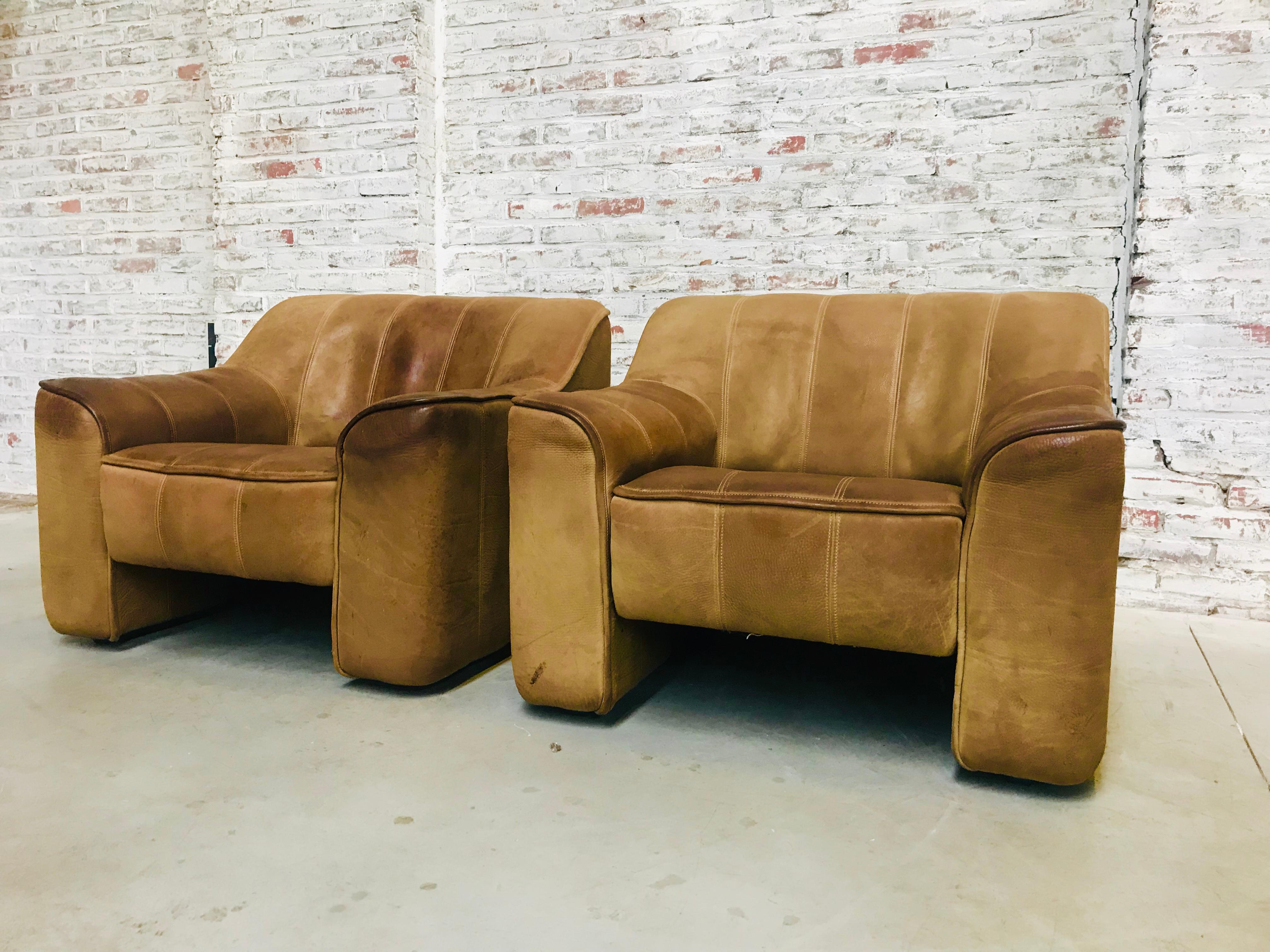 This set of 2 legendary neck leather lounge chairs were designed by the De Sede-team in the 1970s. The manufacturer from Switzerland exhibits inher products the unrivalled traditional craftsmanship of De Sede.