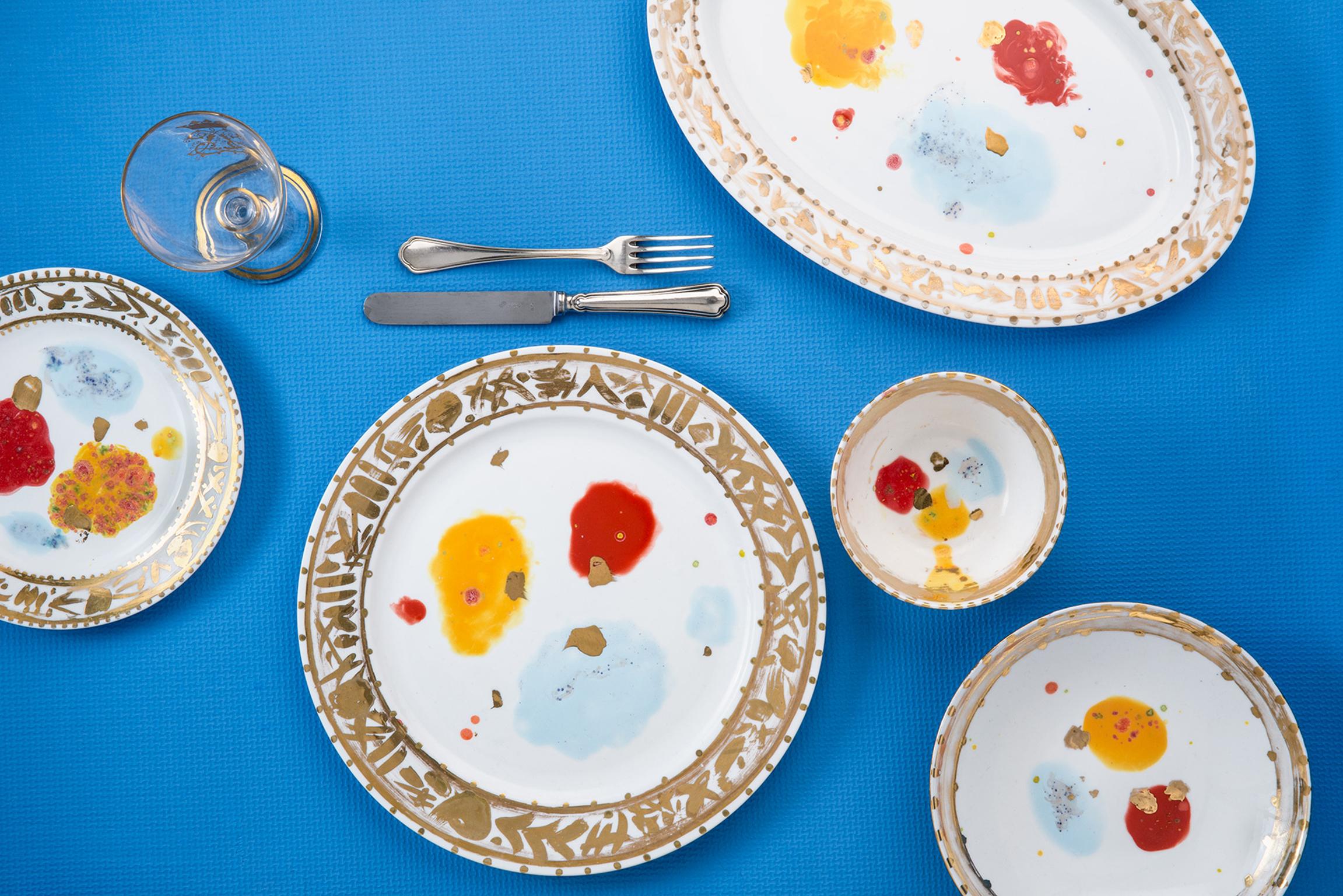 Fabriquée à la main en Italie à partir de la meilleure porcelaine, cette assiette à dessert Caravaggio souligne la tradition grâce à son décor expressif de grandes taches rouges, jaunes et bleu clair, où les passions sont contenues dans un bord doré