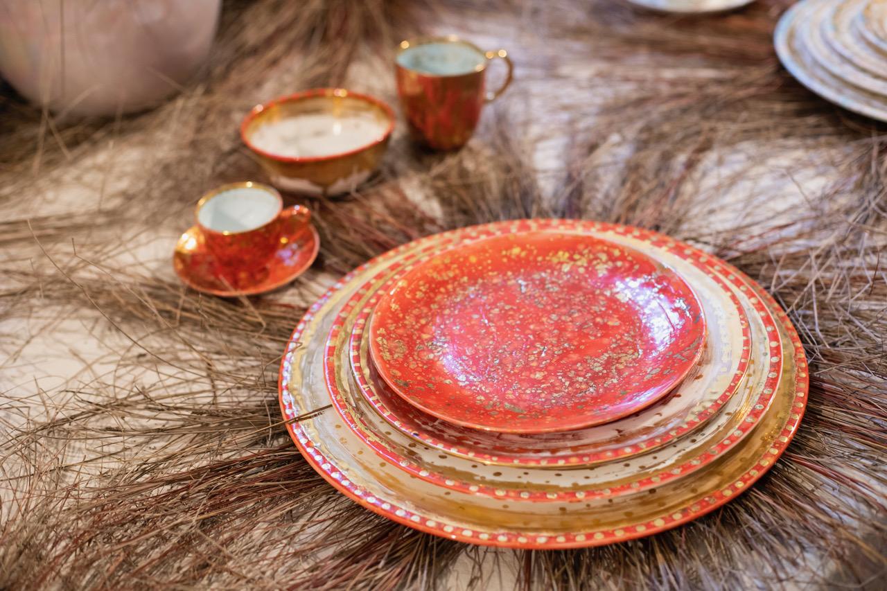 Hand painted in Italy from the finest porcelain, this Scipione dinner plate has the rim sprinkled with a light decor of golden dots and thin circles all around; all around the edge, a narrow, African red rim, punctuated with golden dots; at the