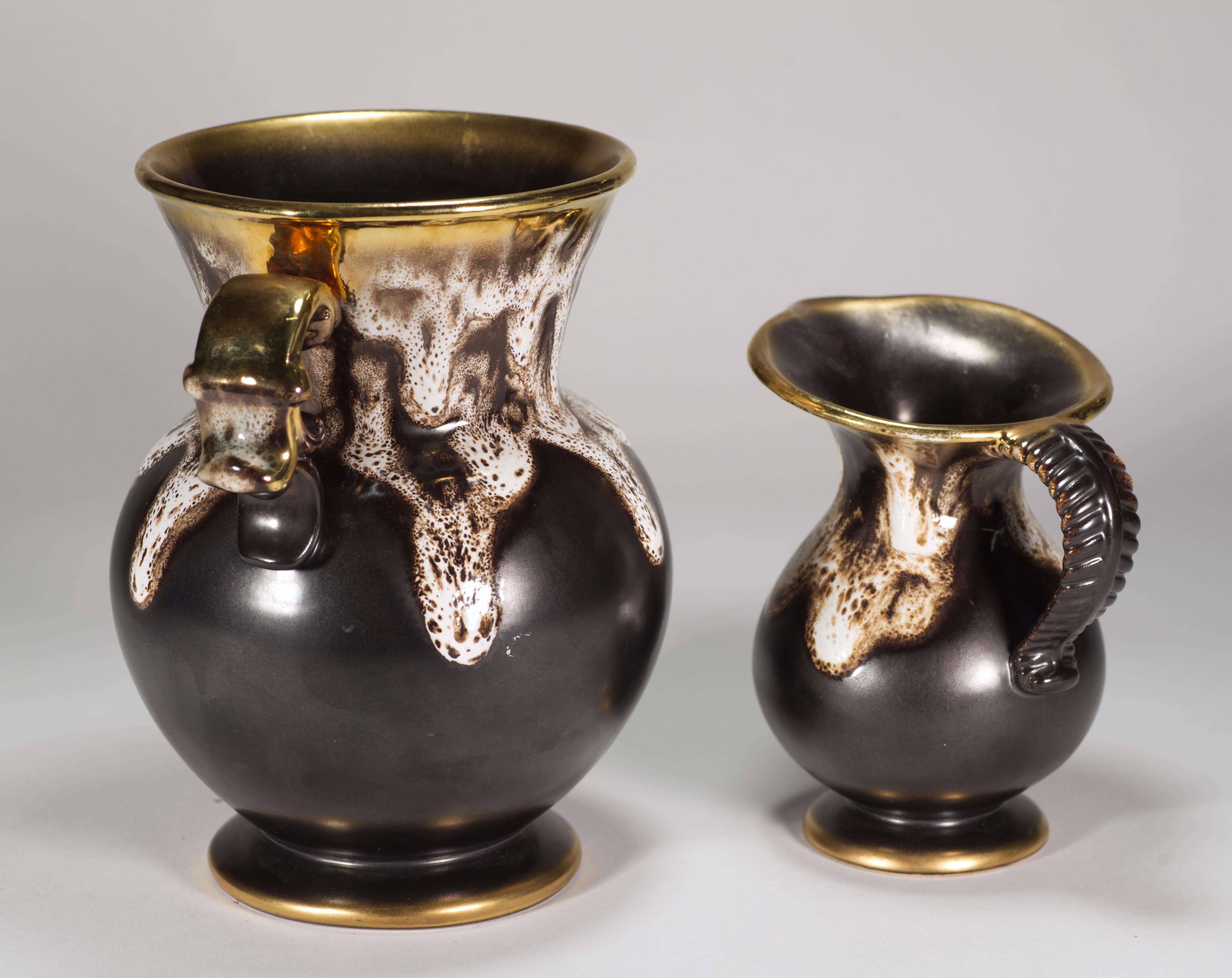  Il set di 2 vasi Mid Century Modern è caratterizzato da uno smalto lavico testurizzato nei colori moka e bianco sporco su sfondo marrone espresso; i manici, le basi e i bordi sono accentuati dall'oro. L'uso di smalti lavici espressivi e altamente