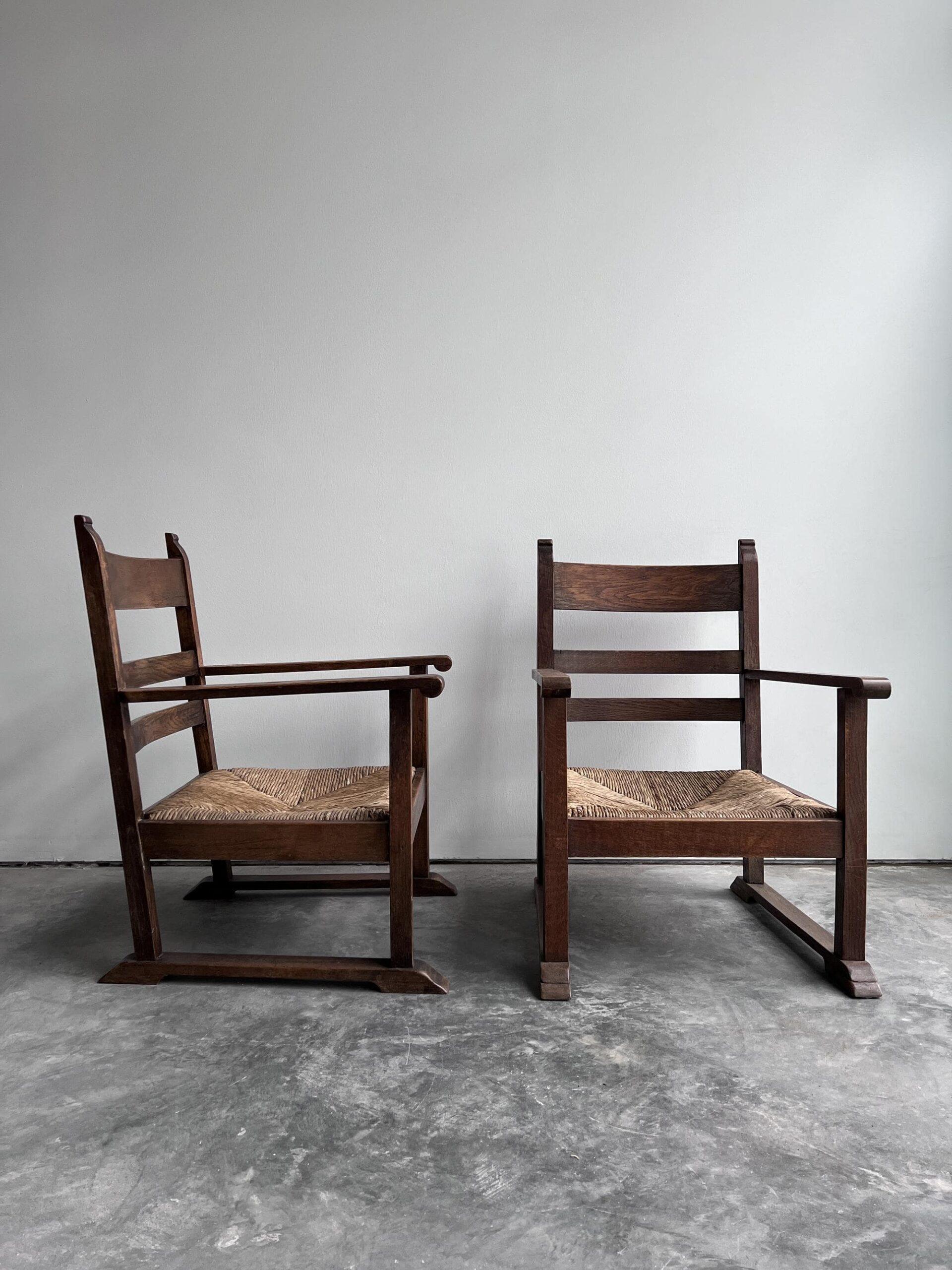 A unique pair of early 20th century Dutch low lounge chairs with original rush seating and solid oak frames. These were most likely intended to be used by the fireplace.