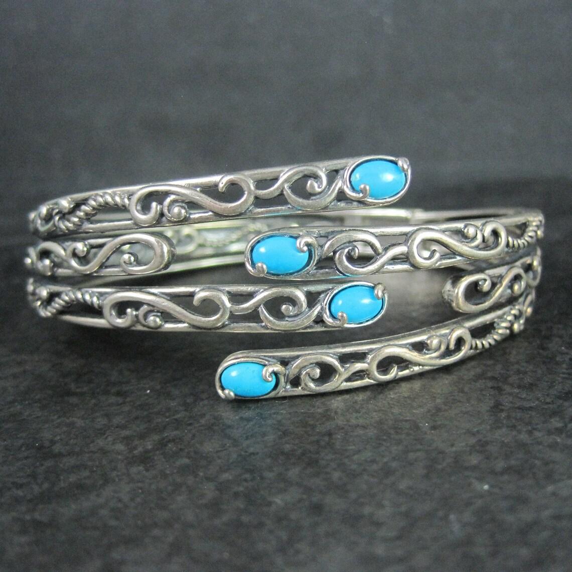 This gorgeous clamper style bangle bracelet is sterling silver with 4 sleeping beauty turquoise gemstones.

This bangle measures 1 inch wide at its face and tapers down to 3/8 of an inch.
Its inner circumference measures 6 3/4 inches. Its inner