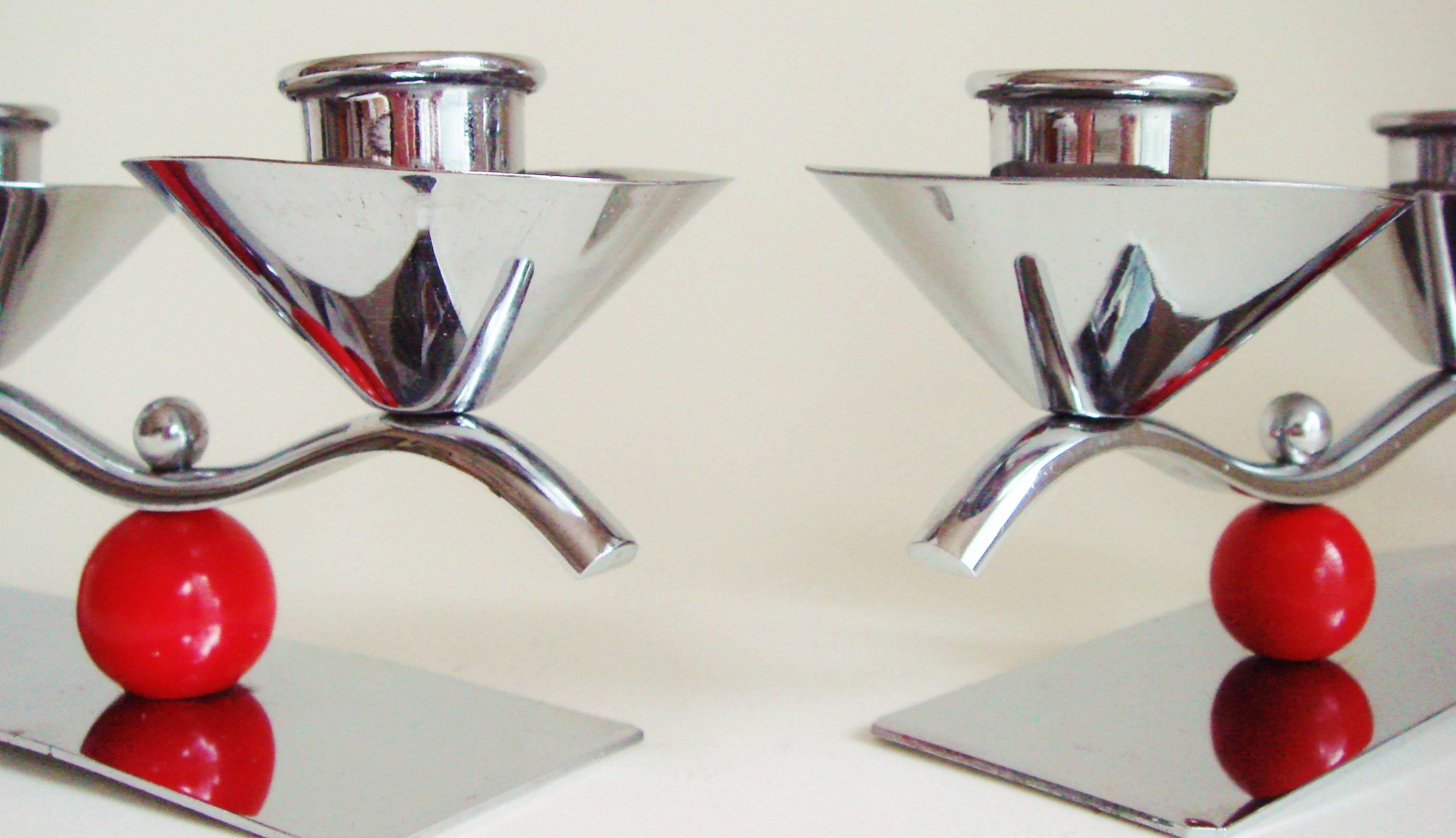 These two English midcentury/Art Deco triple candleholders, though almost identical, are not in fact a pair. One dates from just before the war and features a chrome body with two red lacquered wooden spheres while the other is post war and features