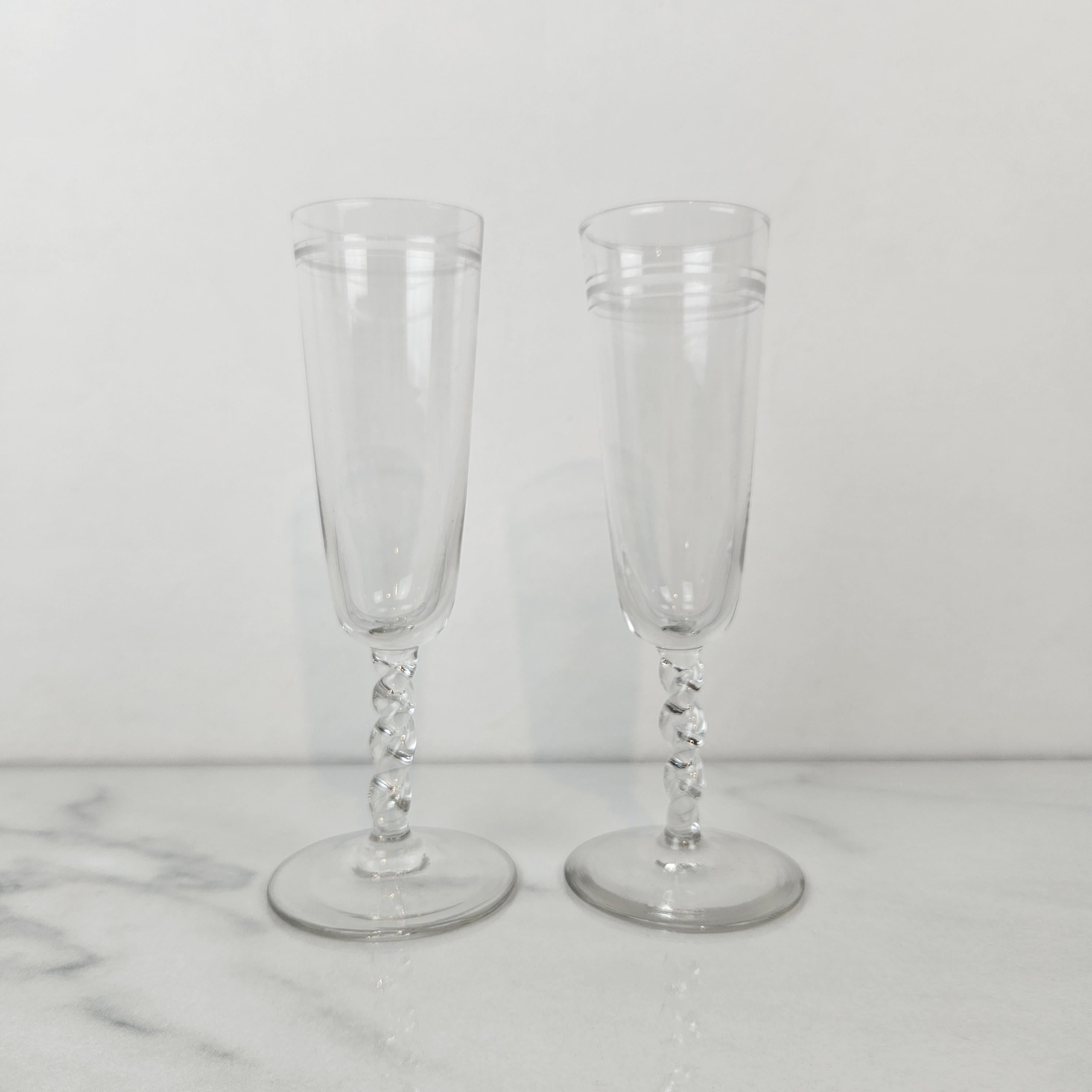 Ein wunderschönes Paar antiker Champagnerflöten, datiert auf ca. 1910. Jede Flöte verfügt über eine hohe, schmale Schale, die in der Nähe des Randes mit subtilen linearen Mustern graviert ist, die dem Design einen Hauch von schlichter Eleganz