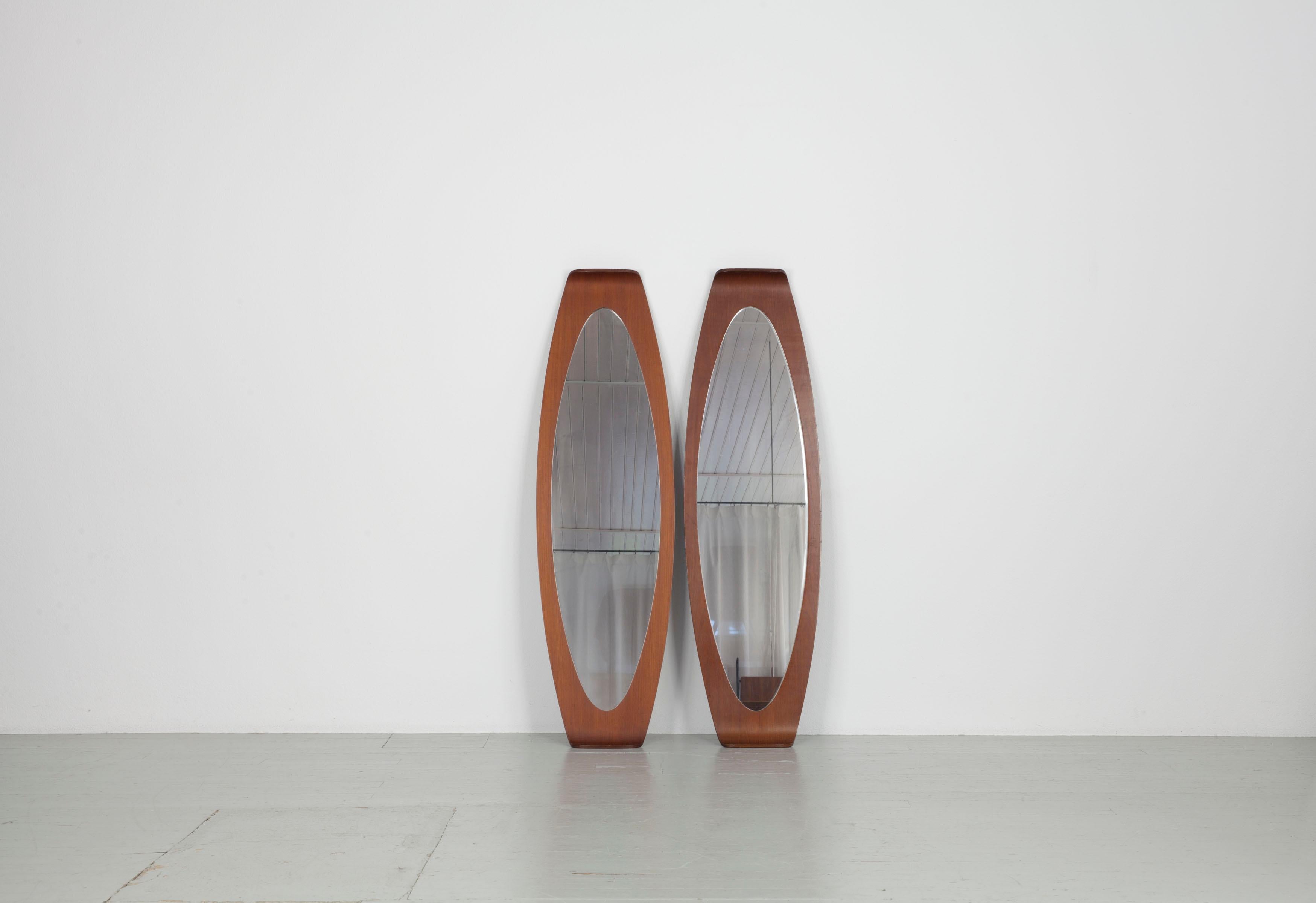 Cet ensemble de miroirs italiens de forme ovale allongée date des années 60. Le décor a été conçu par Franco Campo et Carlo Graffi. Les deux miroirs ont une forme très particulière, la longueur ovale du teck est courbée aux deux extrémités, ce qui