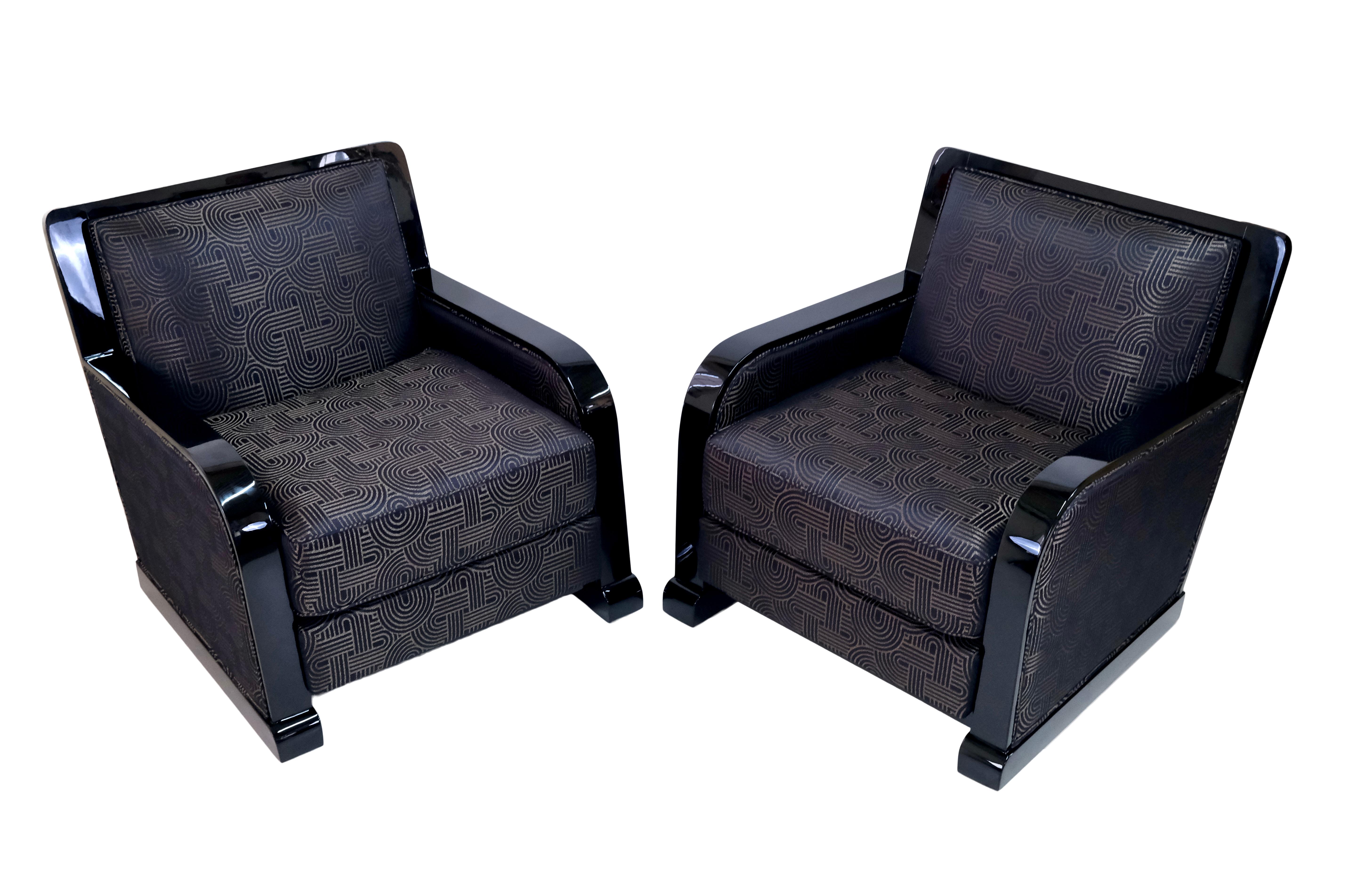 Ein Paar kräftige französische Art-Déco-Sessel. 
Holz in schwarzem Klavierlack, hochglänzend. 
Polsterung aus Stoff mit typischen Art-Déco-Ornamenten in Schwarz- und Goldtönen. 

Diese Clubsessel sind eine Bereicherung für jede Lounge. 
Sie