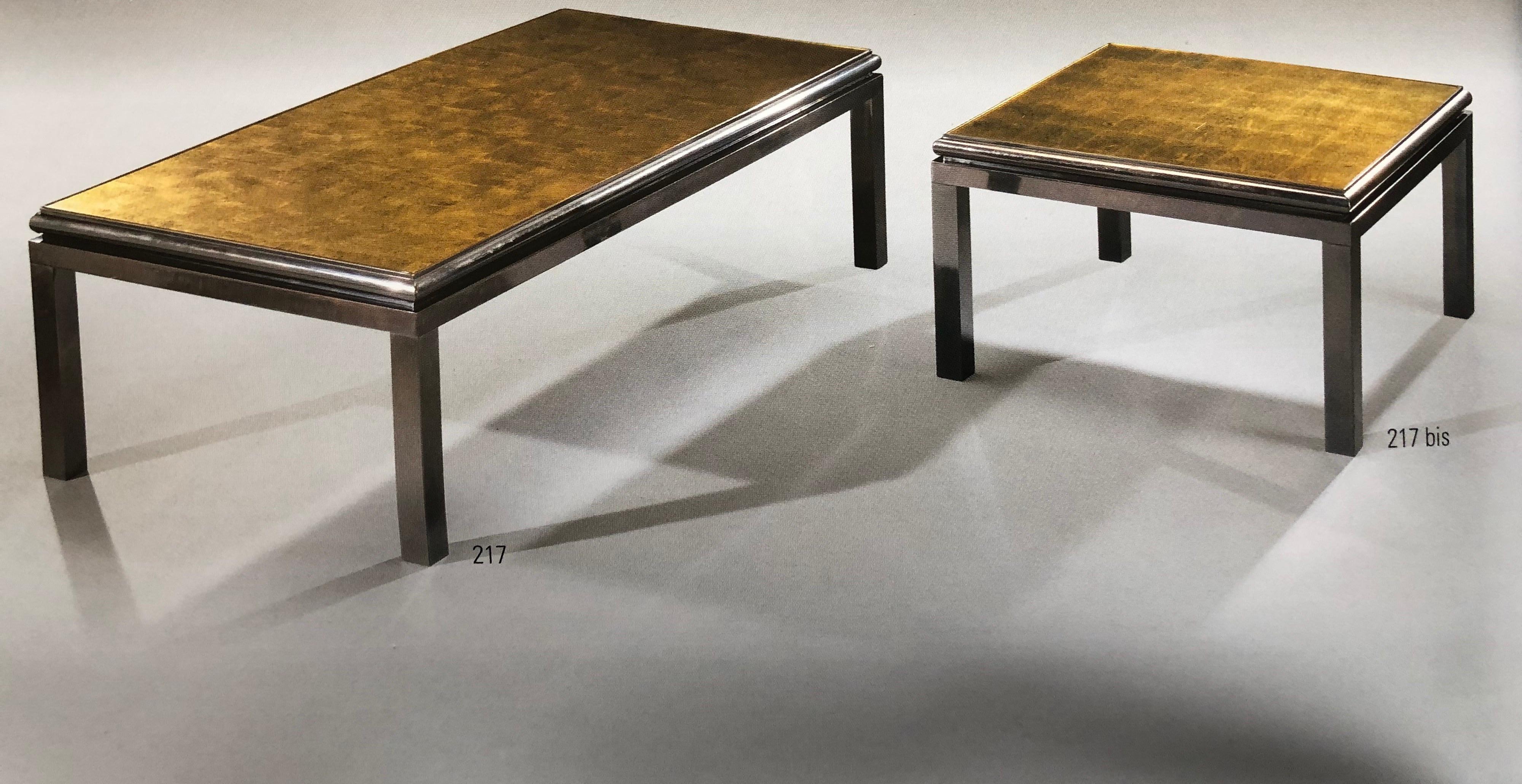 A set of two French Mid-Century Modern coffee tables that form one long table: Each with reverse painted glass top that has been hand gilt in the form of squares. Designed by Guy Lefevre for Maison Jansen with inspiration from a sober, modern