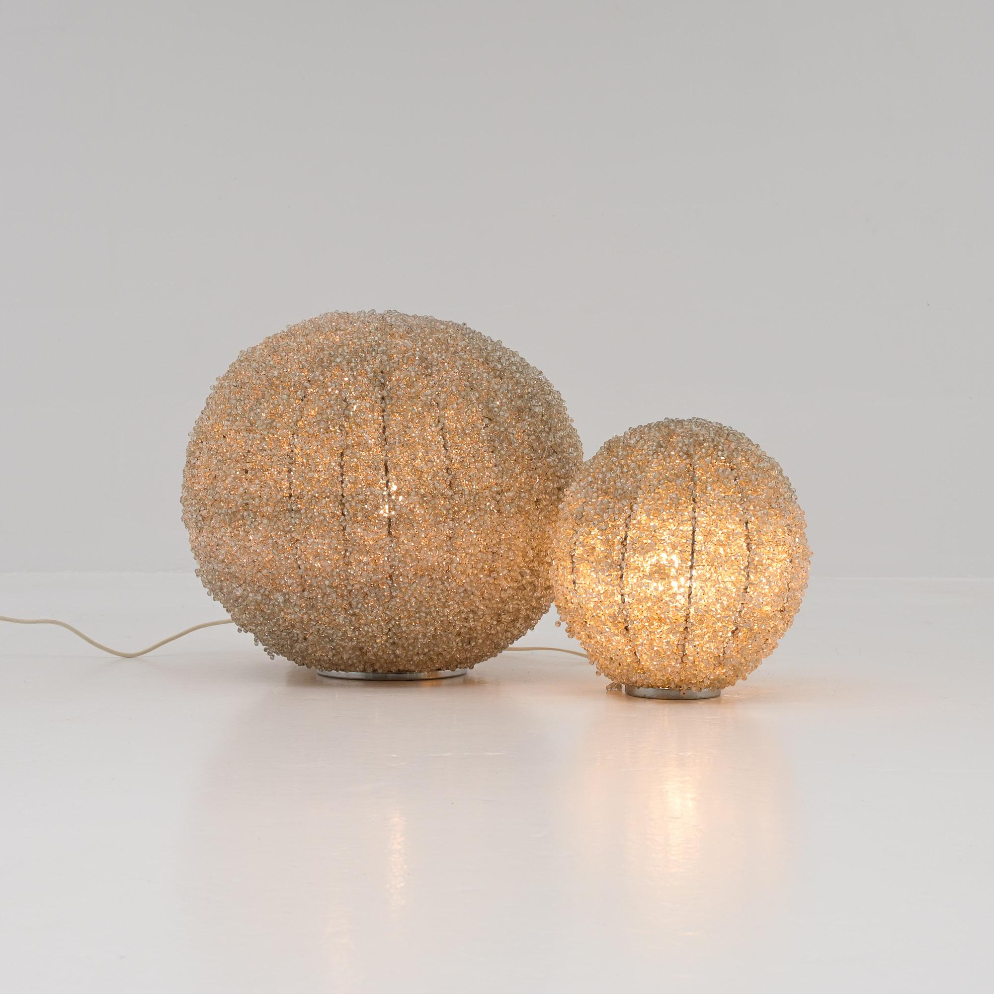 Questo fantastico set di lampade in vetro-perla risale agli anni '70. Sono completamente fatti a mano, immagina che lavoro sia stato. Le perle di vetro combinate con la luce danno un effetto molto bello e unico.

Le lampade si adattano a qualsiasi