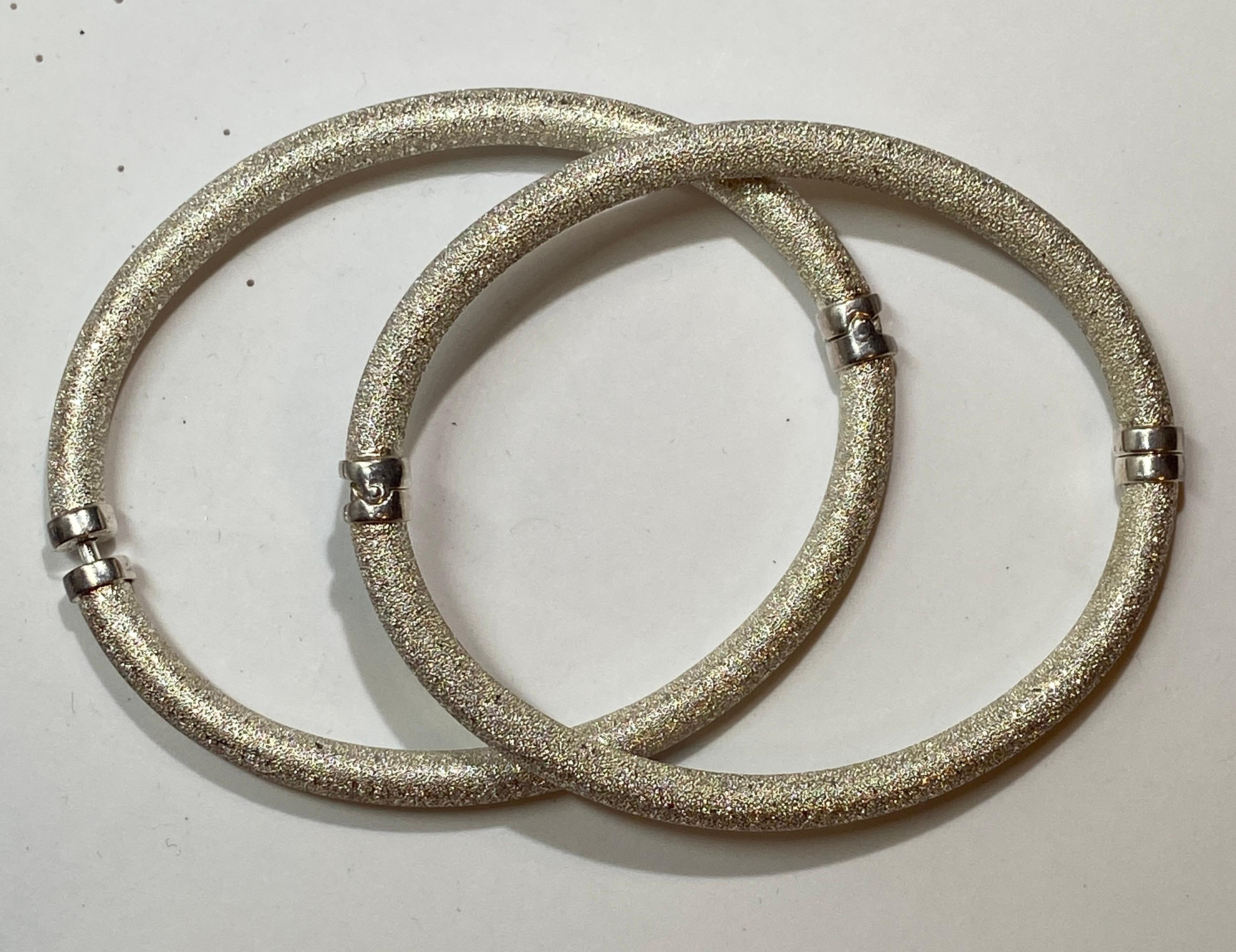 Wonderful set of 2 bracelets in a glittering 'Diamond-Cut' finish in sterling silver, and accented with polished sterling silver at the middle and closings. The closing is fitted with a 'click' clasp. The interior circumference measures 7 1/4