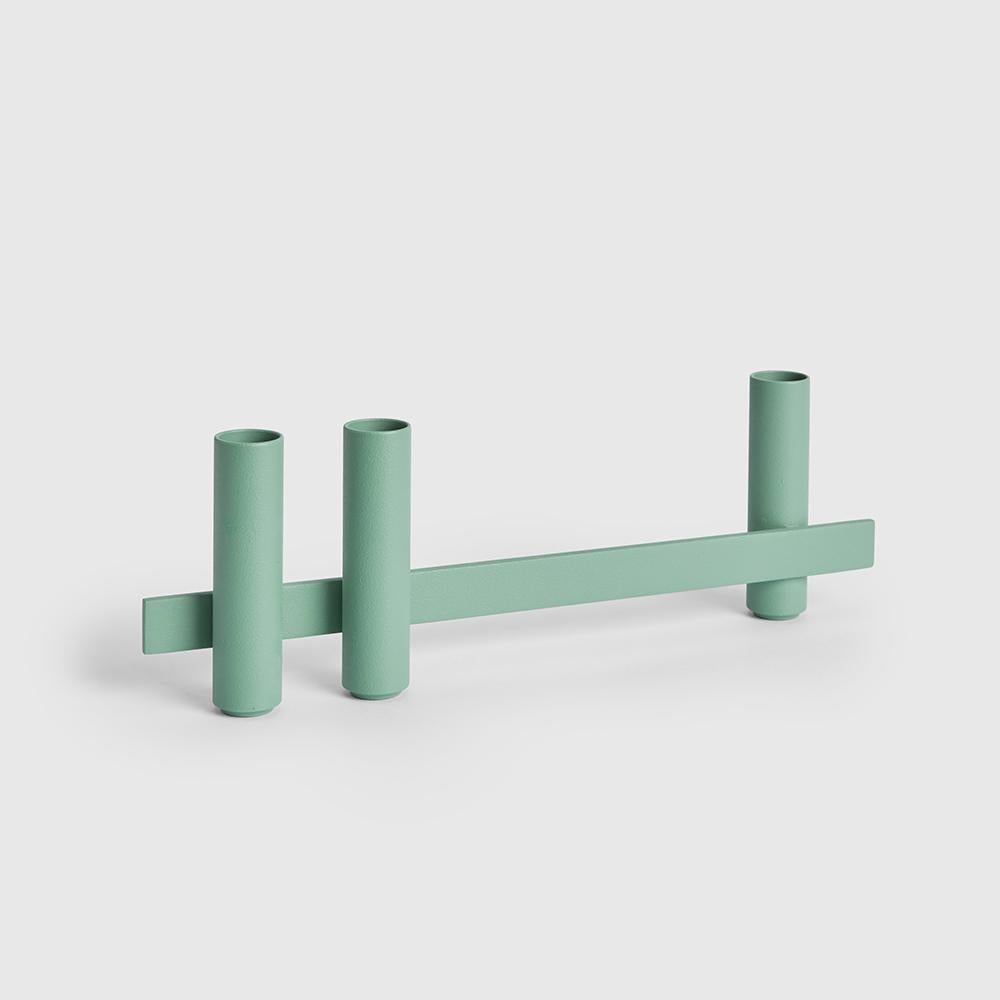 Set of 2 green candle holders by Mason Editions.
Dimensions: 31 × 5 × 10 cm
Materials: Iron
Colors: Black, matte 24K gold, cotto, sage green and light grey.

Consisting of a longitudinal metal bar supporting cylindrical elements on both sides,
