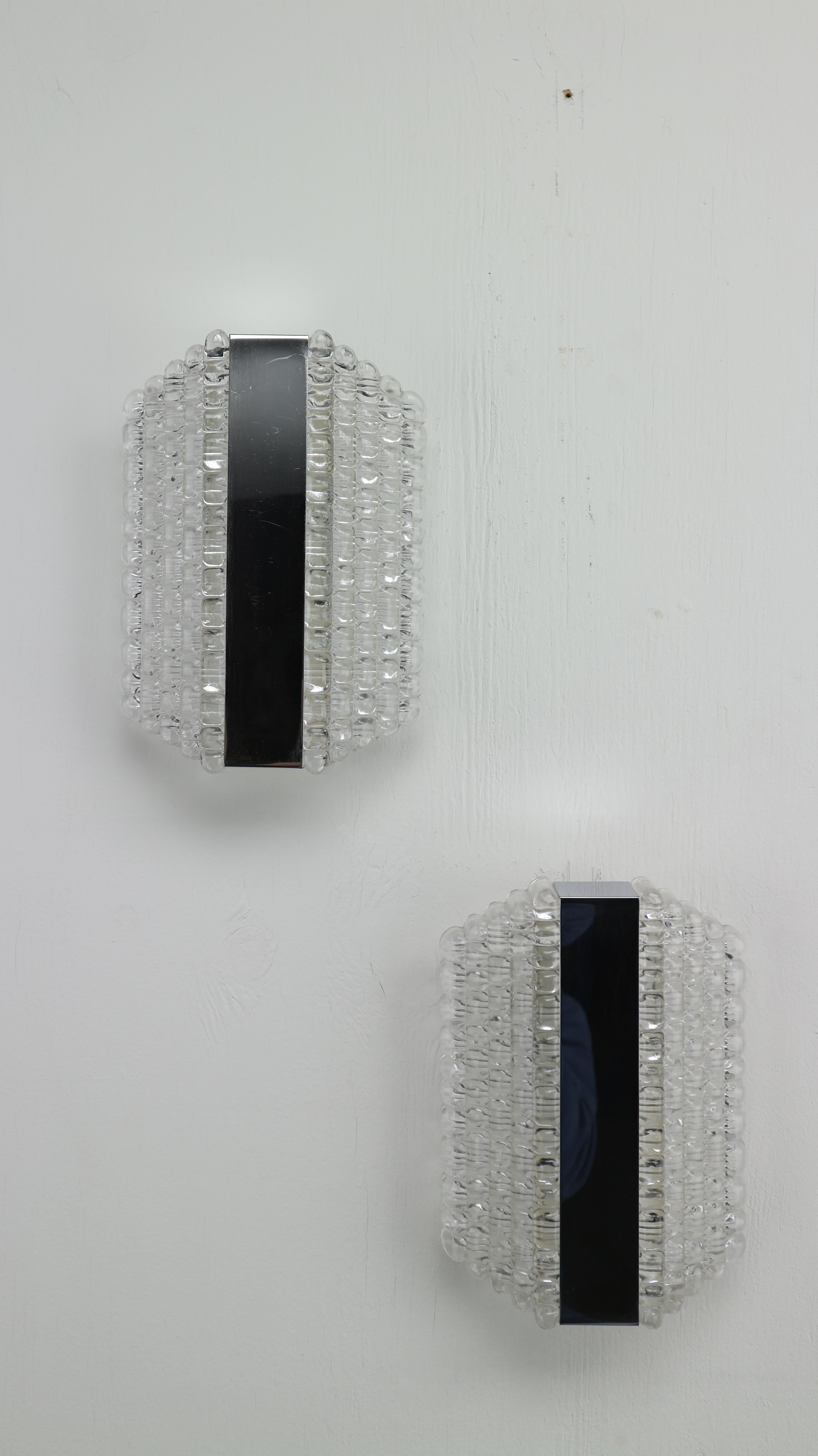 Set of two hanging wall lamps designed by Kaiser Leuchten in 1960s.
The peaces working in order and gives a warm lightening.
Chrome plating mirror details and crystal glass.