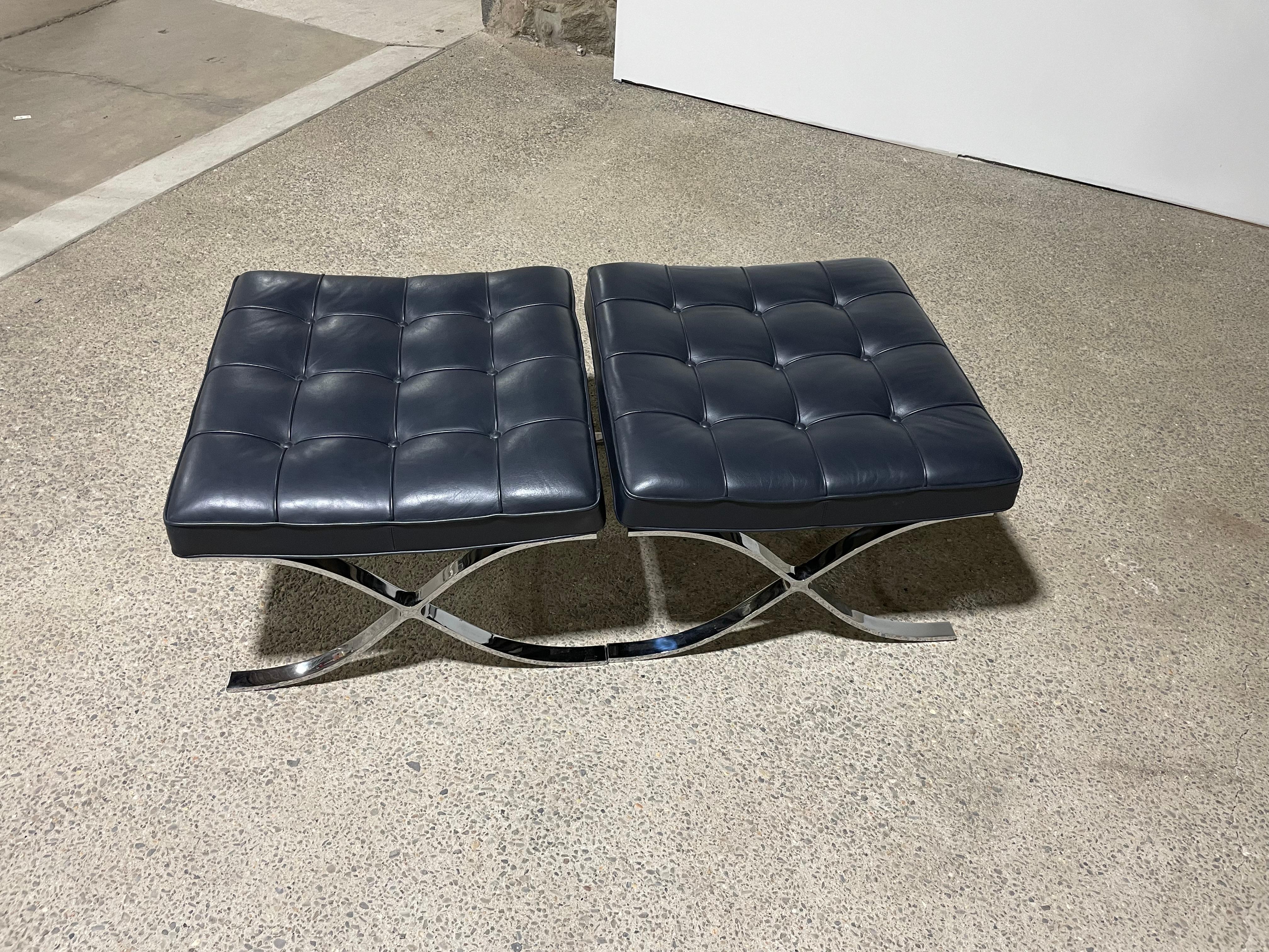 Fantastic pair of authentic Knoll. Barcelona ottomans with engraving on leg and tag underneath the seat. 

The pair are matching dark blue leather. It is likely that the leather type is Sabrina, Marine Blue, with a retail price of over $5000 per