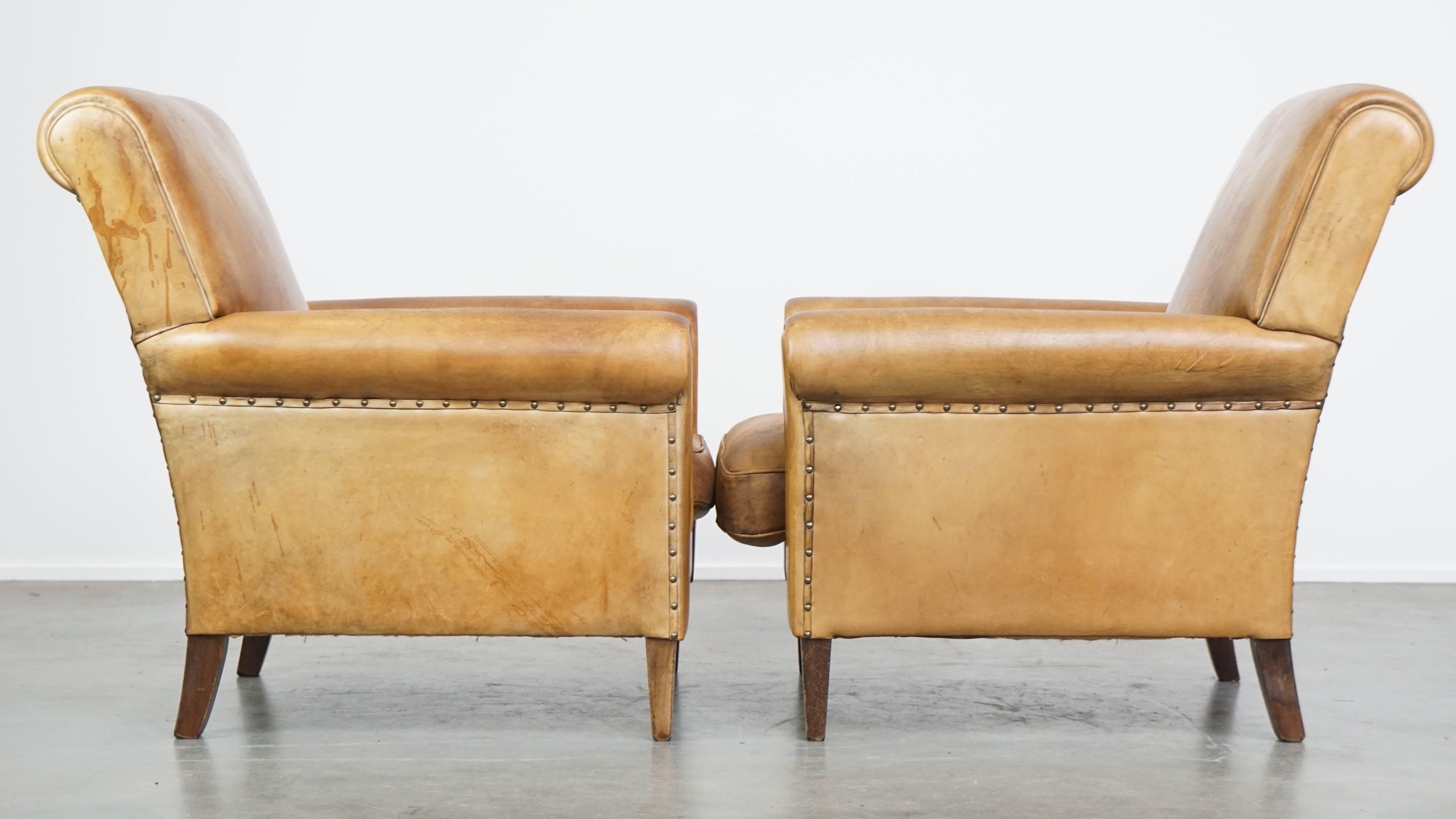 Cet ensemble de deux superbes fauteuils en cuir de mouton s'intègre sans effort dans presque tous les intérieurs. Avec leurs formes élégantes et leur patine magnifiquement vieillie, ces chaises vintage exsudent le caractère et le style