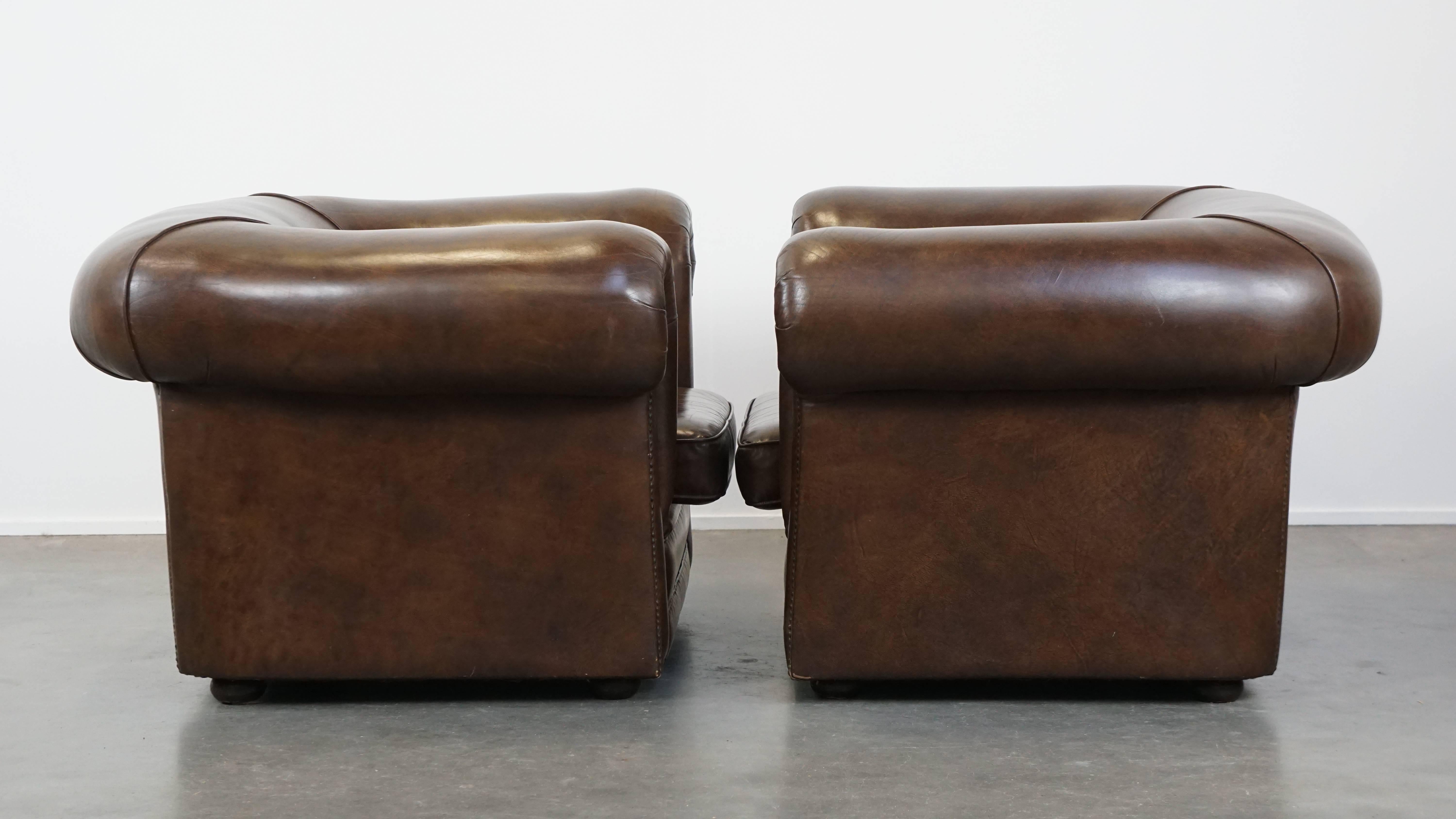 Vous aimez le charme des meubles Chesterfield, mais préférez une finition lisse sans touffes de boutons profondes ? Cet ensemble de deux grands fauteuils en cuir lisse est exactement ce qu'il vous faut !

Leur couleur foncée et leur élégante