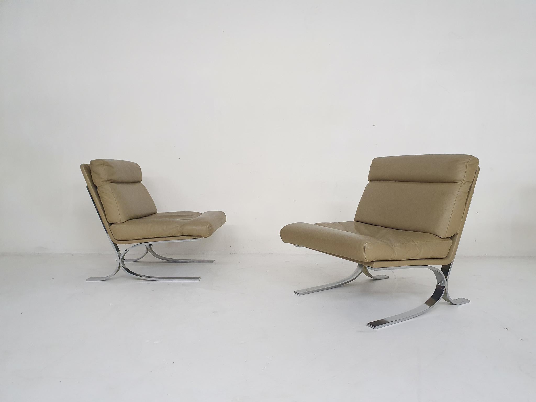 Set of two high quality chromed metal lounge chairs with an off-white or beige leather upholstery.

We think they are designed by Paul Tuttle for Strässle, Switzerland. They chairs are very similar in design to his 