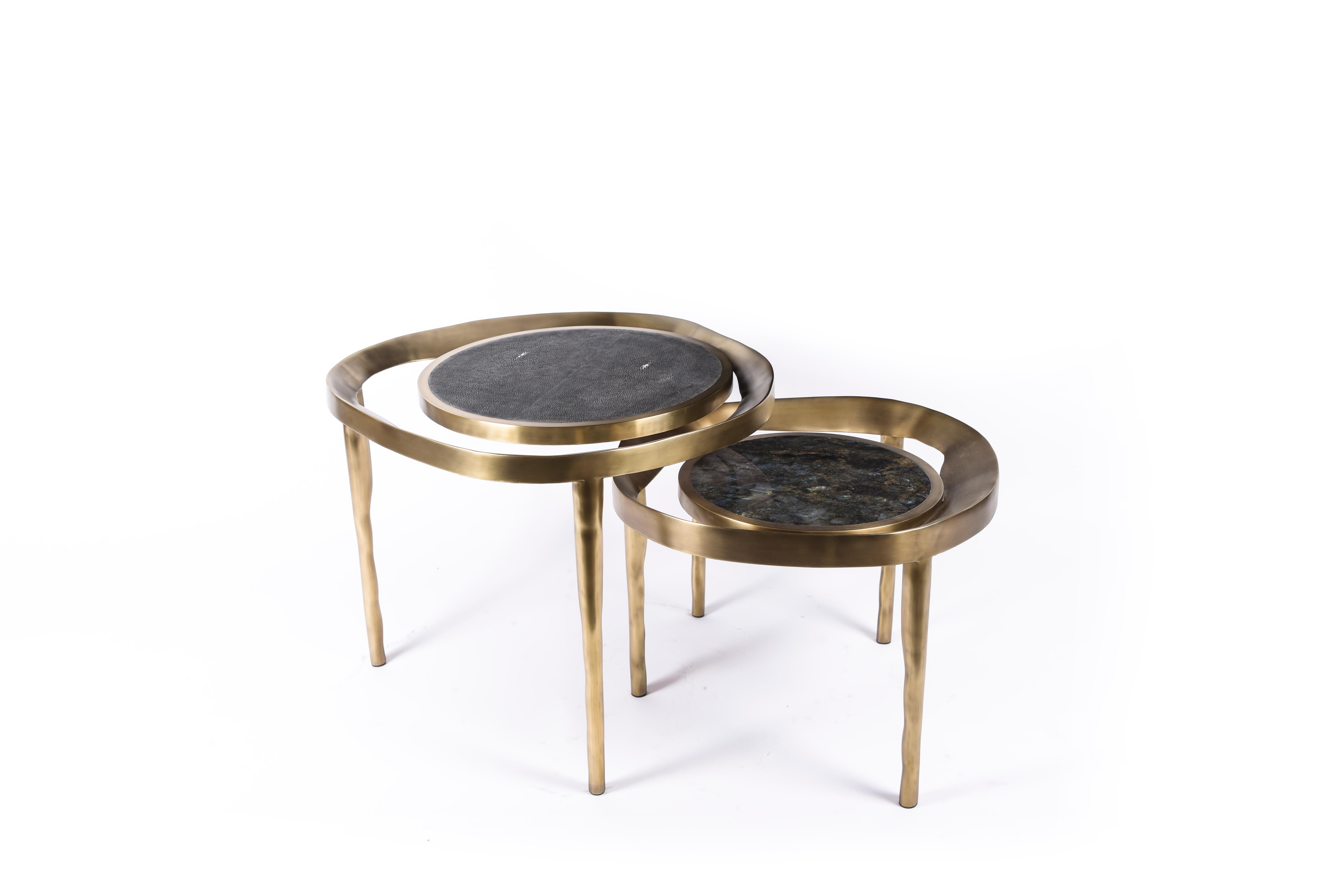 The set of 2 Lily Melting Coffee Tables are a whimsical and dramatic piece for any space. The amorphous-shaped bronze-patina brass frame morphs onto the bumpy shaped legs. The floating circular tops are inlaid in coal black shagreen and Lemurian