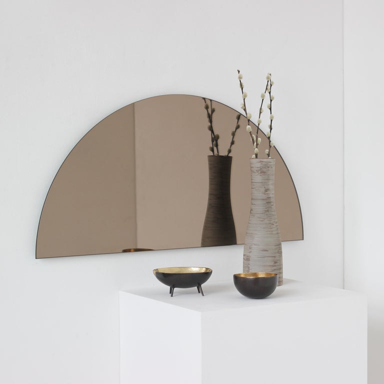 Set of 2 original and minimalist half-moon bronze tinted frameless mirrors with a floating effect. Quality design that ensures the mirror sits perfectly parallel to the wall. Designed and made in London, UK. 

Each piece is fitted with professional