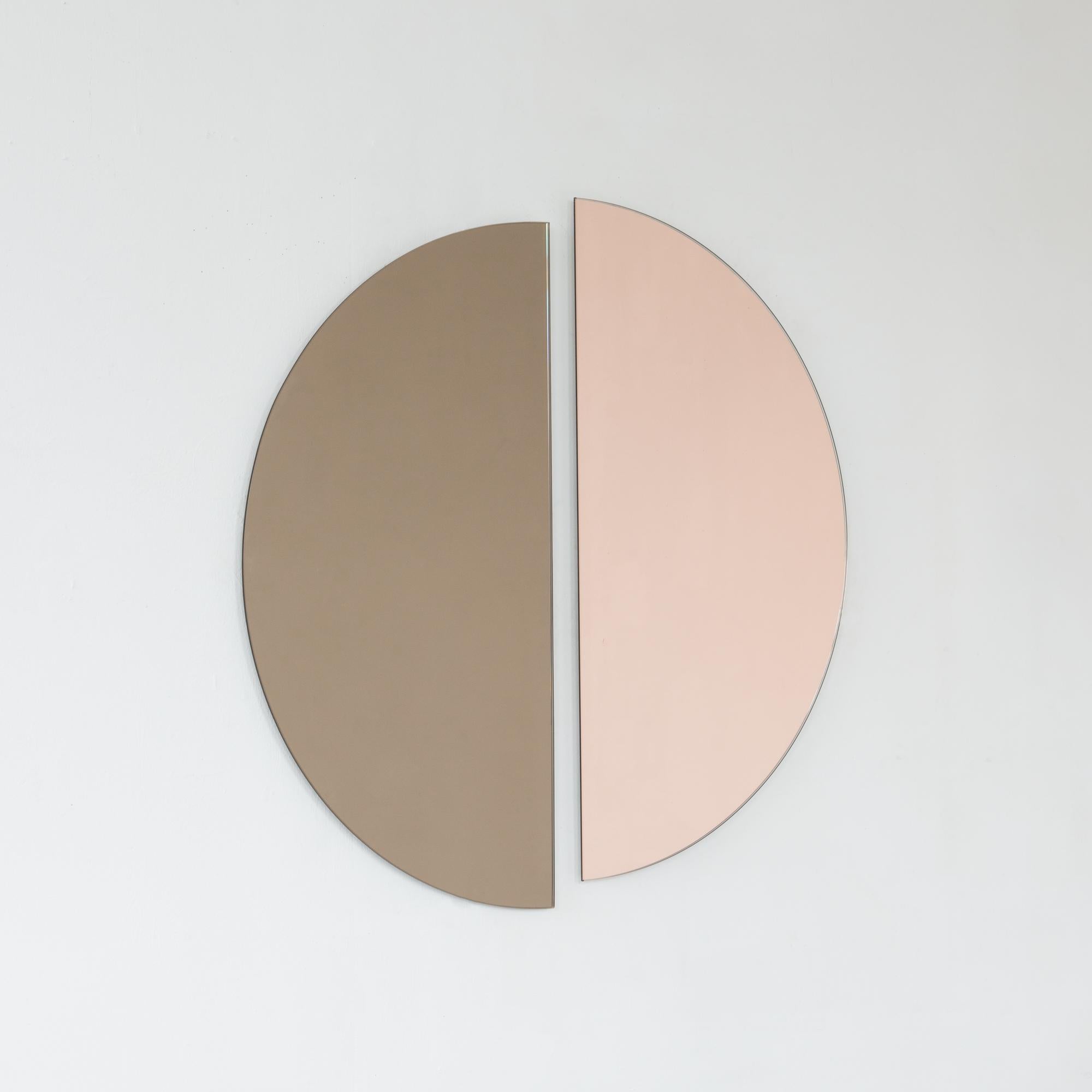 Set of two minimalist half-moon Luna™ bronze + rose gold (peach) tinted frameless mirrors with a floating effect. Fitted with a quality and ingenious hanging system for a flexible installation in 4 different directions. Designed and made in London,