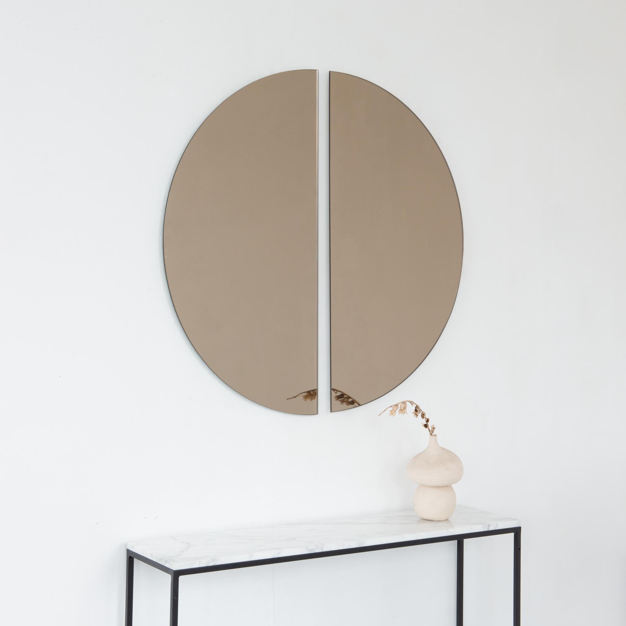 Set of two minimalist half-moon Luna™ bronze tinted frameless mirrors with a floating effect. Fitted with a quality and ingenious hanging system for a flexible installation in 4 different directions. Designed and made in London, UK. 

The backing